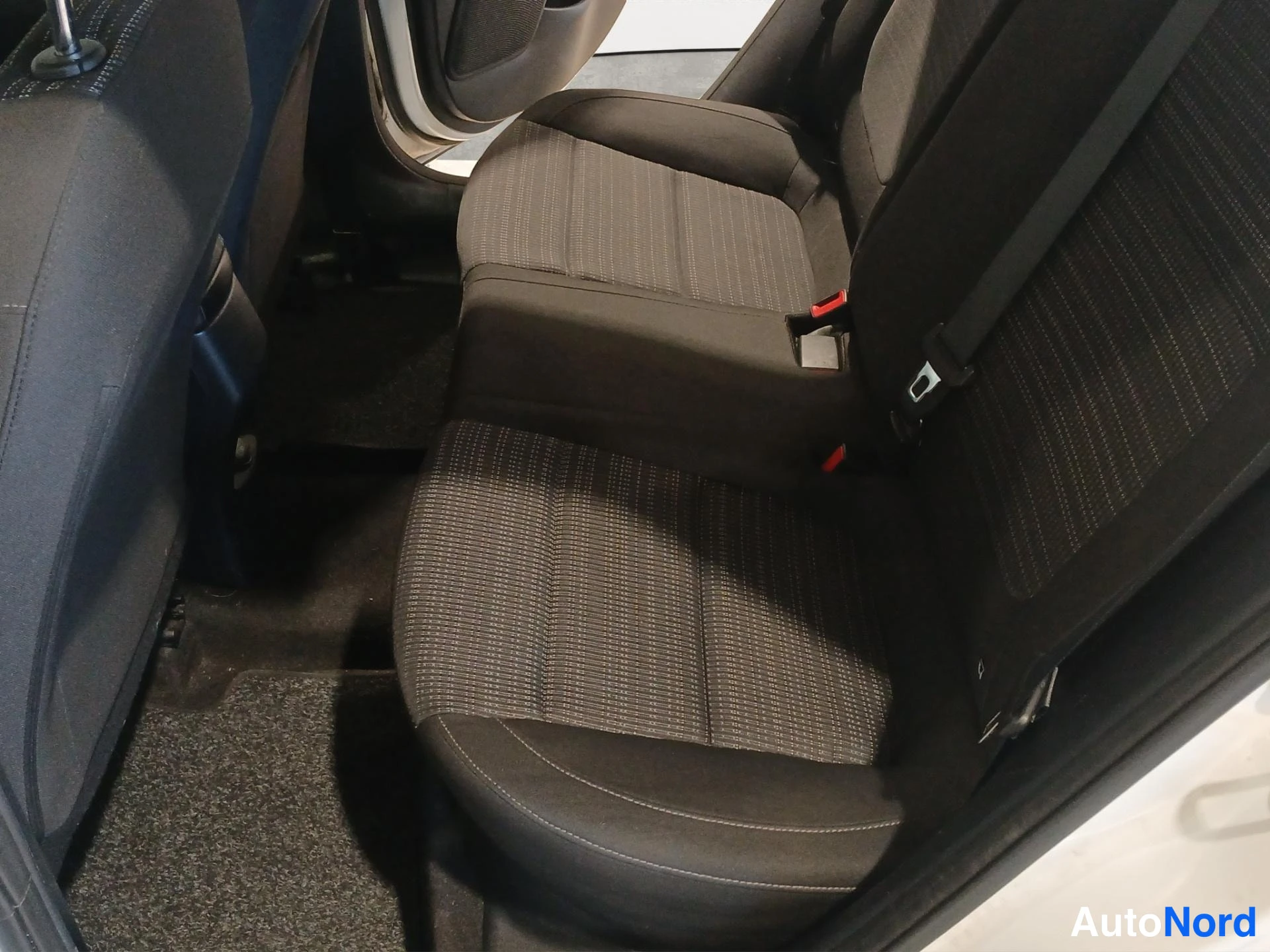Muu: Takaistuimet kuvattuina ovista, tummat kankaat, matot ja turvavyöt näkyvät.