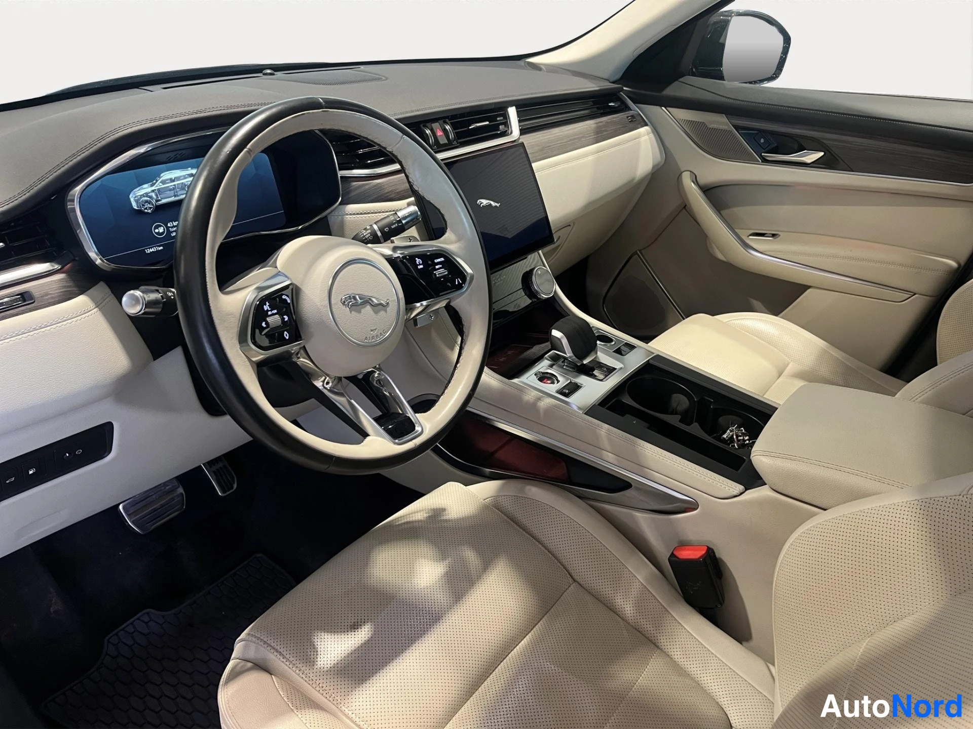 Muu: Jaguar F-Pace ohjaamo kuvattuna kuljettajan ovelta: nelipuolainen ohjauspyörä, viisto keskinäyttö, beiget nahkapenkit ja automaattivaihteen valitsin.