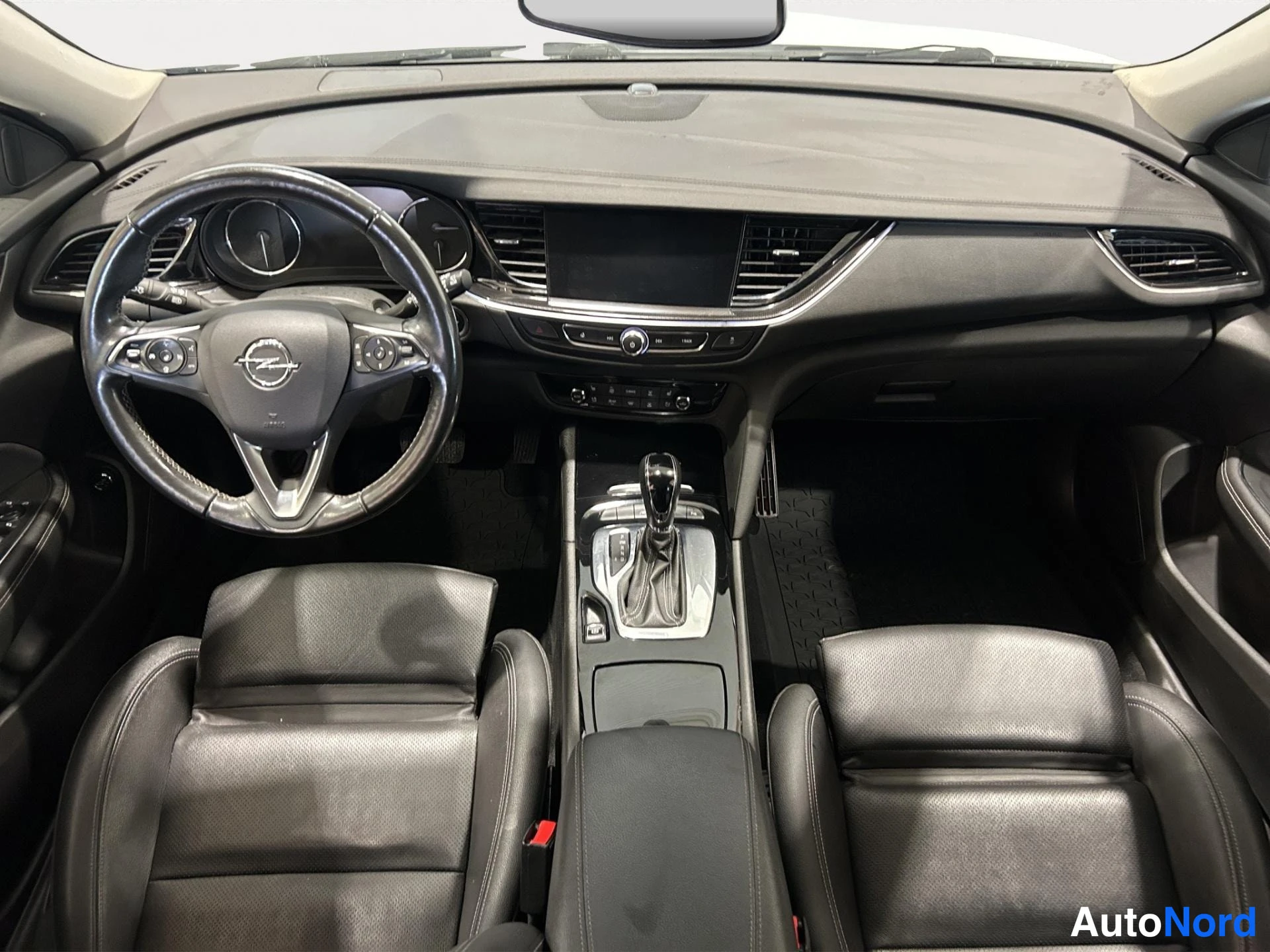 Yksityiskohta: Ohjaamo mustan sisustan: Opel-ohjauspyörä, automaattivaihteisto, kosketusnäyttö ja kaksi nahkaistuinta.