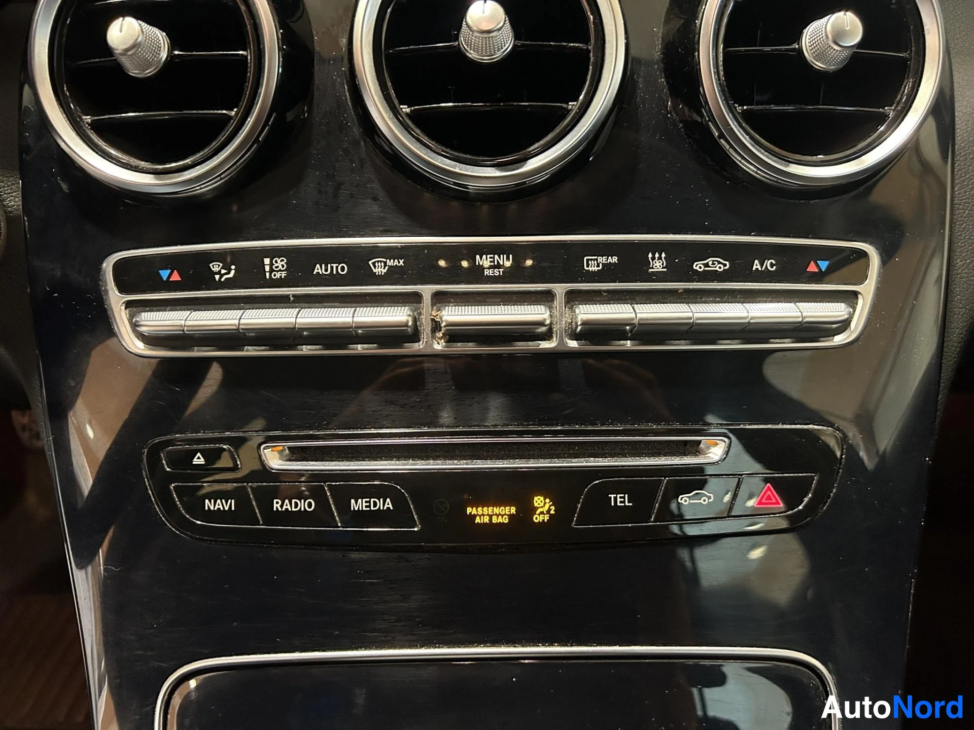 Muu: Keskikäytävän ilmastointipaneeli, jossa AUTO-, MAX- ja A/C-napit sekä NAVI-, RADIO-, MEDIA- ja TEL-napit.
