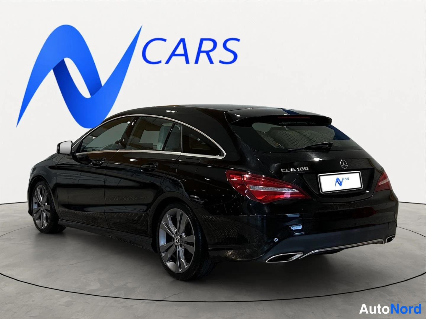 Takaviisto: Mustan Mercedes-Benz CLA Shooting Braken takakulmanäkymä oikealta, takaluukissa CLA 180 -merkintä ja takavalot näkyvät.