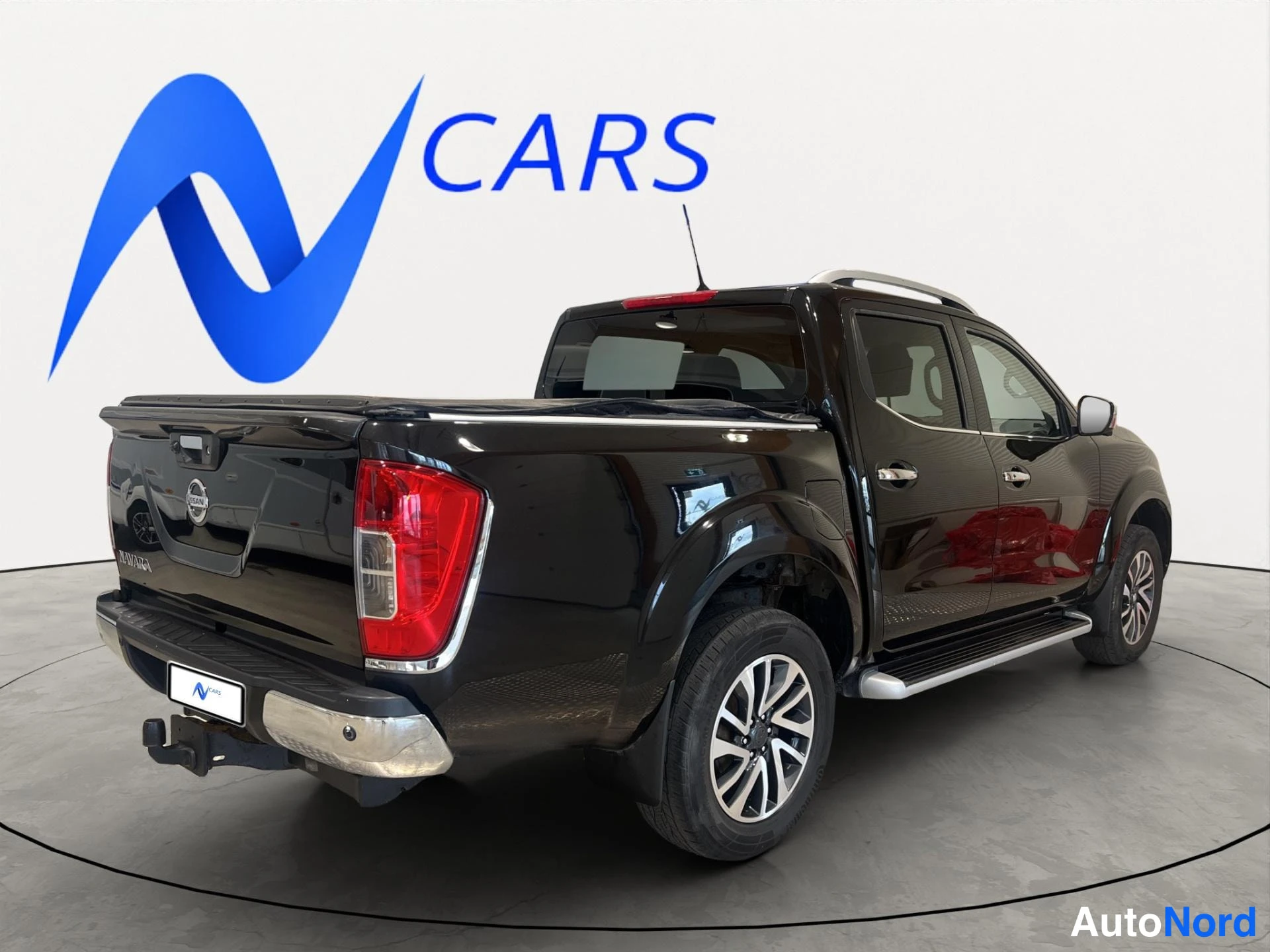 Takaviisto: Musta Nissan Navara takakulmasta vasemmalta, lava ja takavalot näkyvät