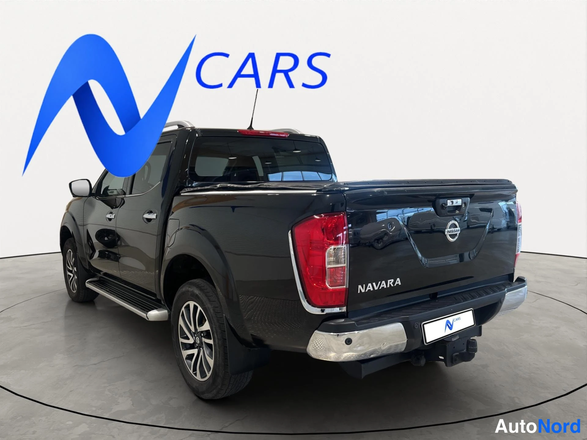 Takaviisto: Musta Nissan Navara takakulmasta, NAVARA-teksti lava Selässä ja takavalo näkyvät
