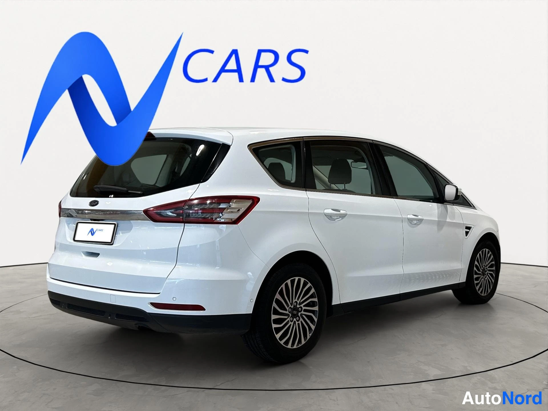 Takaviisto: Valkoinen Ford S-MAX -tilasmaasturi kulmassa takaa vasemmalta, takaosa ja sivu näkyvissä.