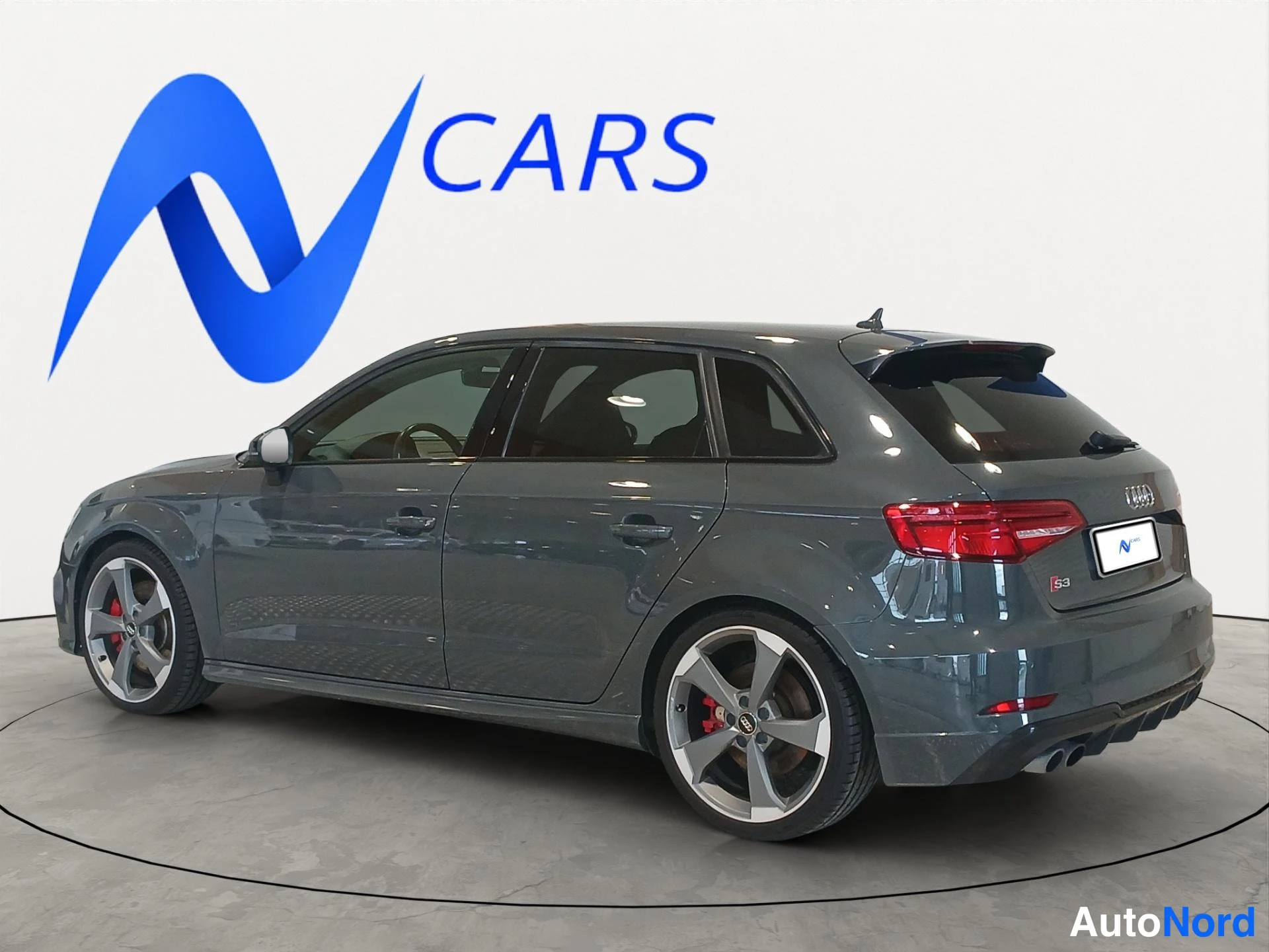 Takaviisto: Audi A3 Sportback -mallin takakolmasosan kuva; tummanharmaa koripinta, kattospoileri, punaiset takavalot, Audi-merkki takaluukissa ja kaksoispakoputket, ympyräa