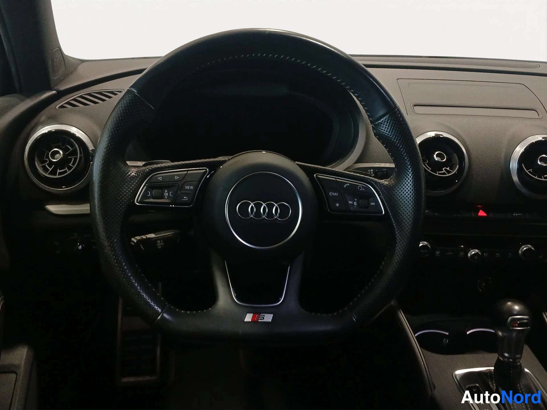 Yksityiskohta: Audi-ohjauspyörä S-tunnuksella, ilmastointiaukot ja vaihtajan kahva näkyvissä.