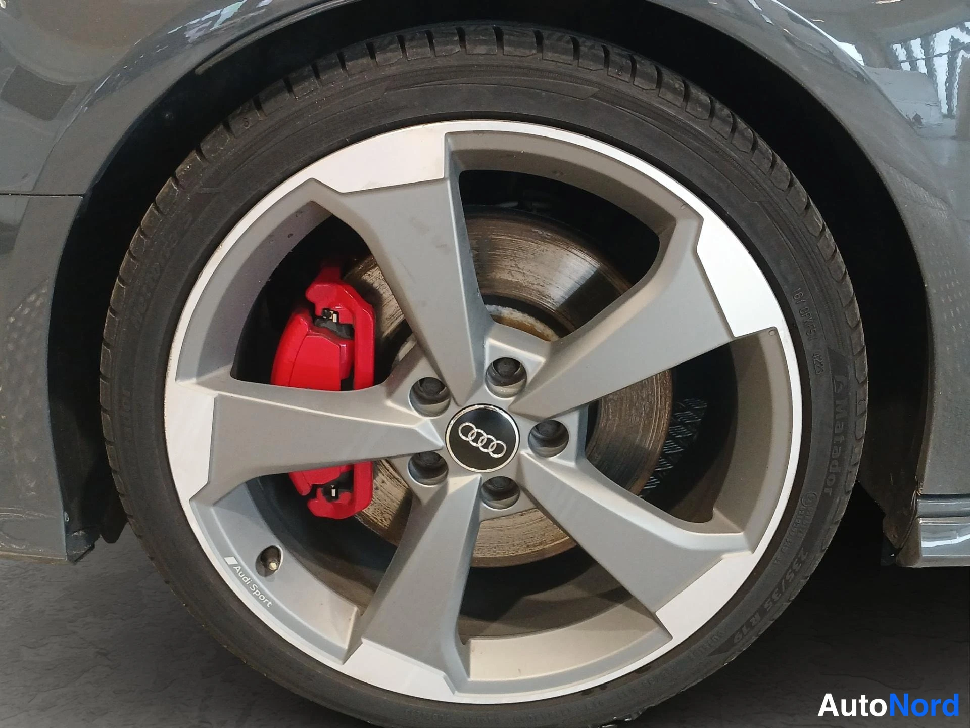 Muu: Audi-mallisesta viisipuolikkovanteesta lähikuva, punainen jarrusatula ja Audi-merkki näkyvissä.