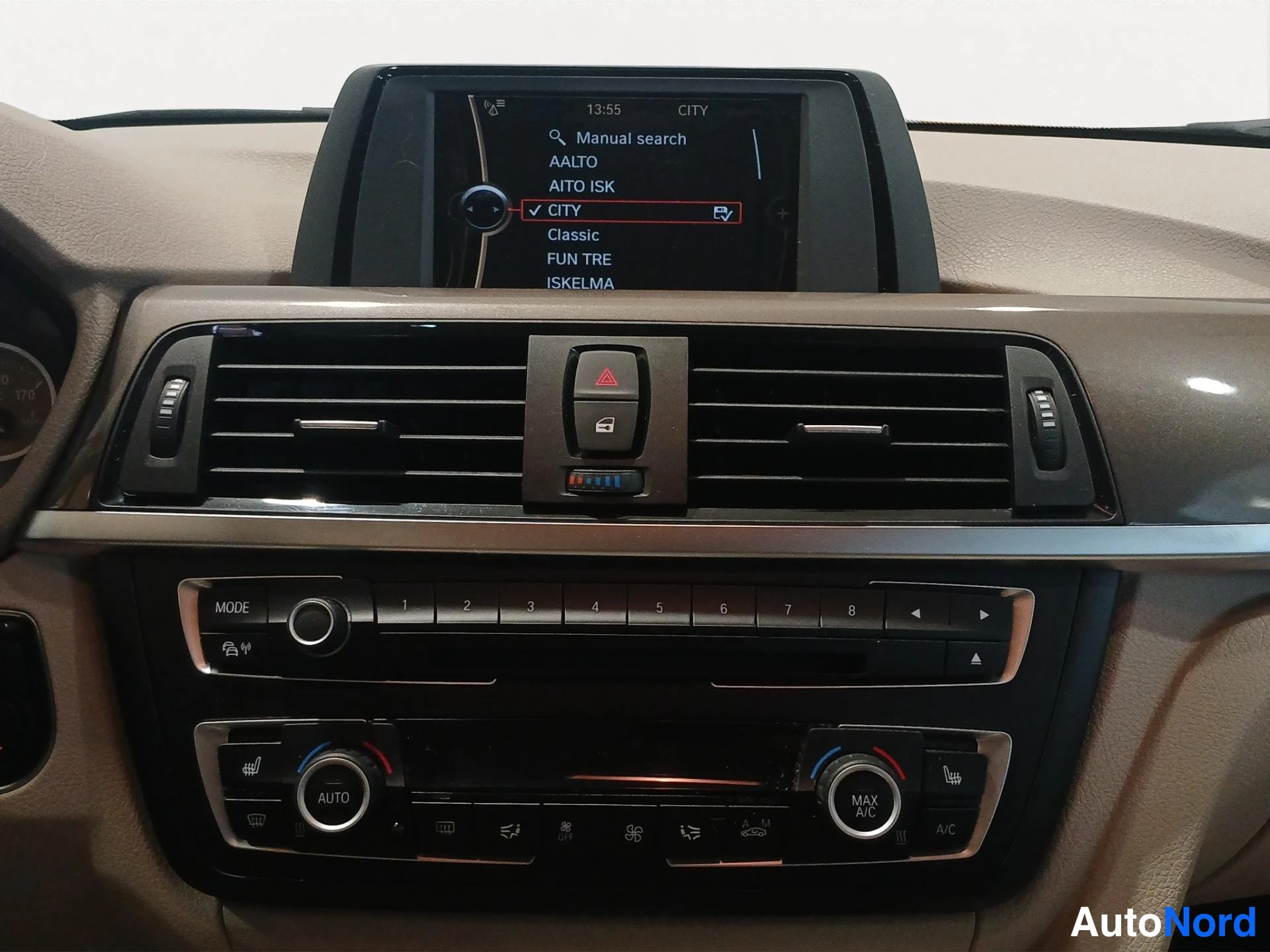Edestä: Kojelaudan keskusosio: radiopaneeli numeronäppäimillä 1-8, AUTO ja MAX A/S -sätökset, radiovisuu readout sekä mahdollinen istuinpainehälytys
