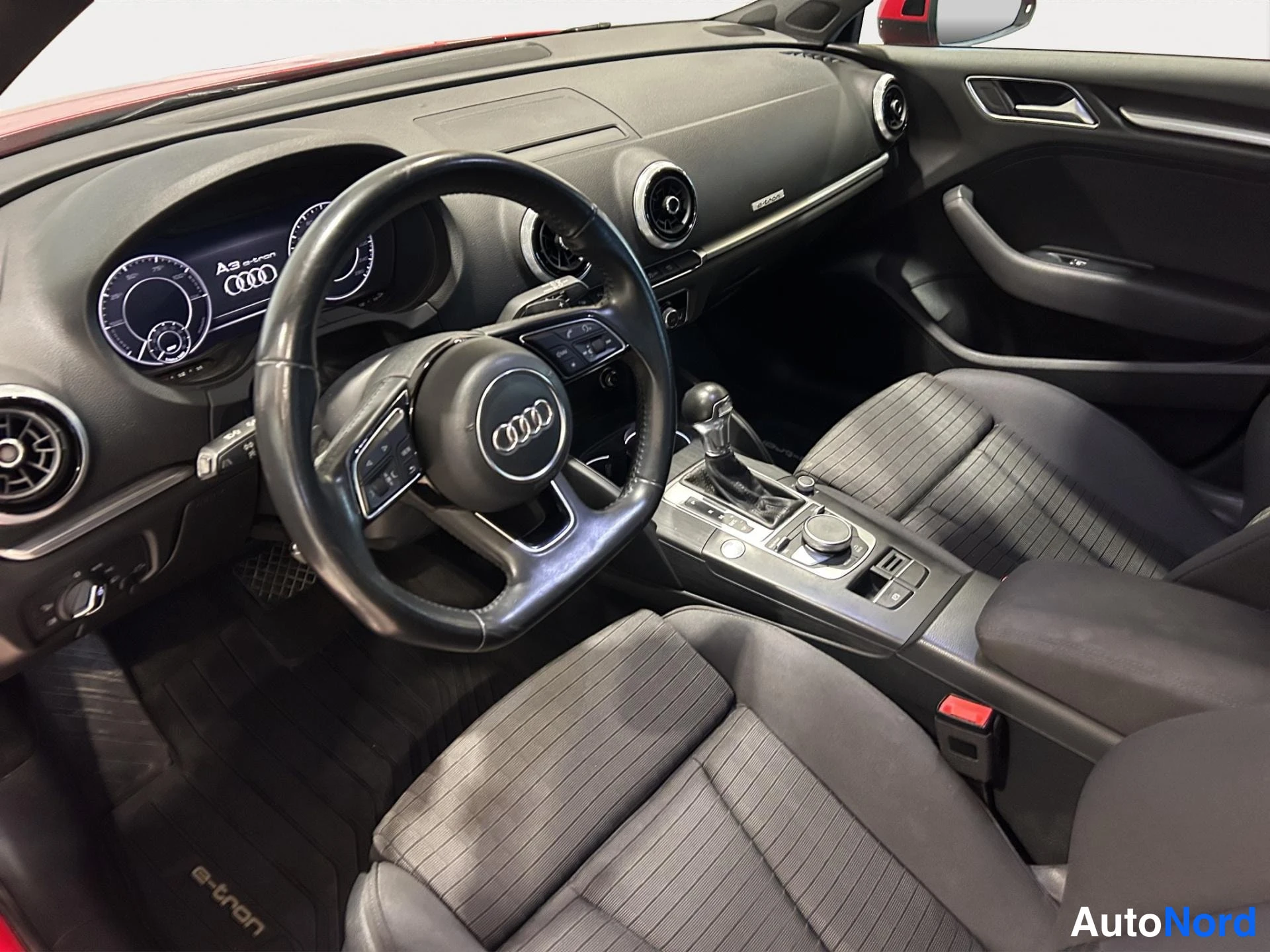 Edestä: Auton ohjaamo: Audi-ohjauspyörä, digitaalinen A3 e-tron mittaristo, automatic-vaihdekeila ja kaksi tummaa etuistuinta.