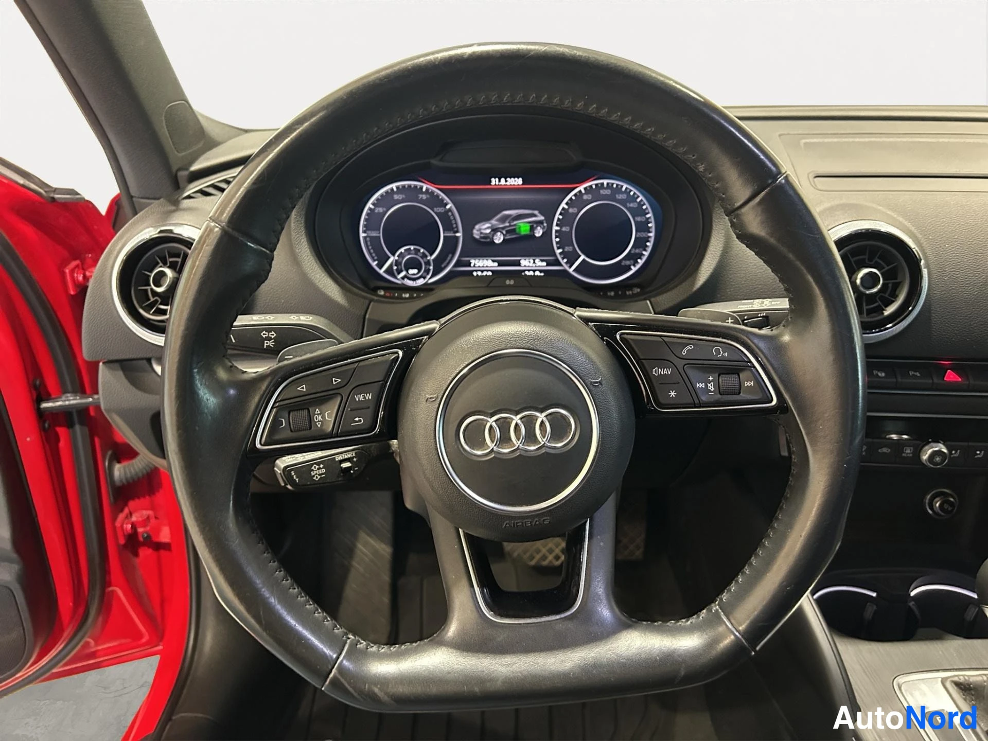 Muu: Audi-ohjauspyörä ja digitaalinen kojetaulu lähikuvassa; kojetaulussa näkyy ajoneuvon latauksen grafiikka.