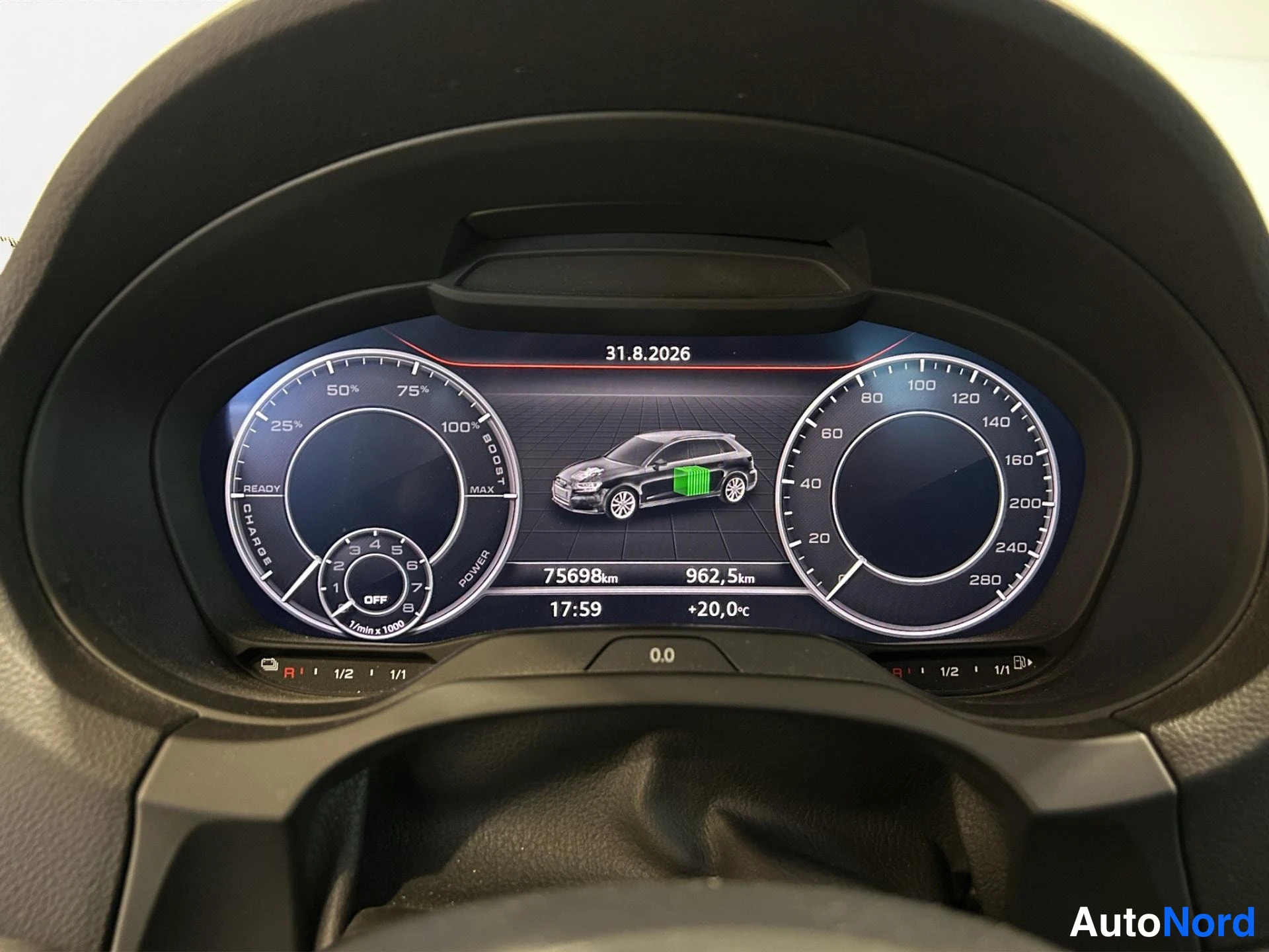 Yksityiskohta: Audi A3:n mittaristön näyttö, jossa näkyy lataustila- ja power-mittarit, ajoneuvon kuva akulla, matkamittari 75698 km, 962,5 km, päivämäärä 31.8.2026, kellonaik