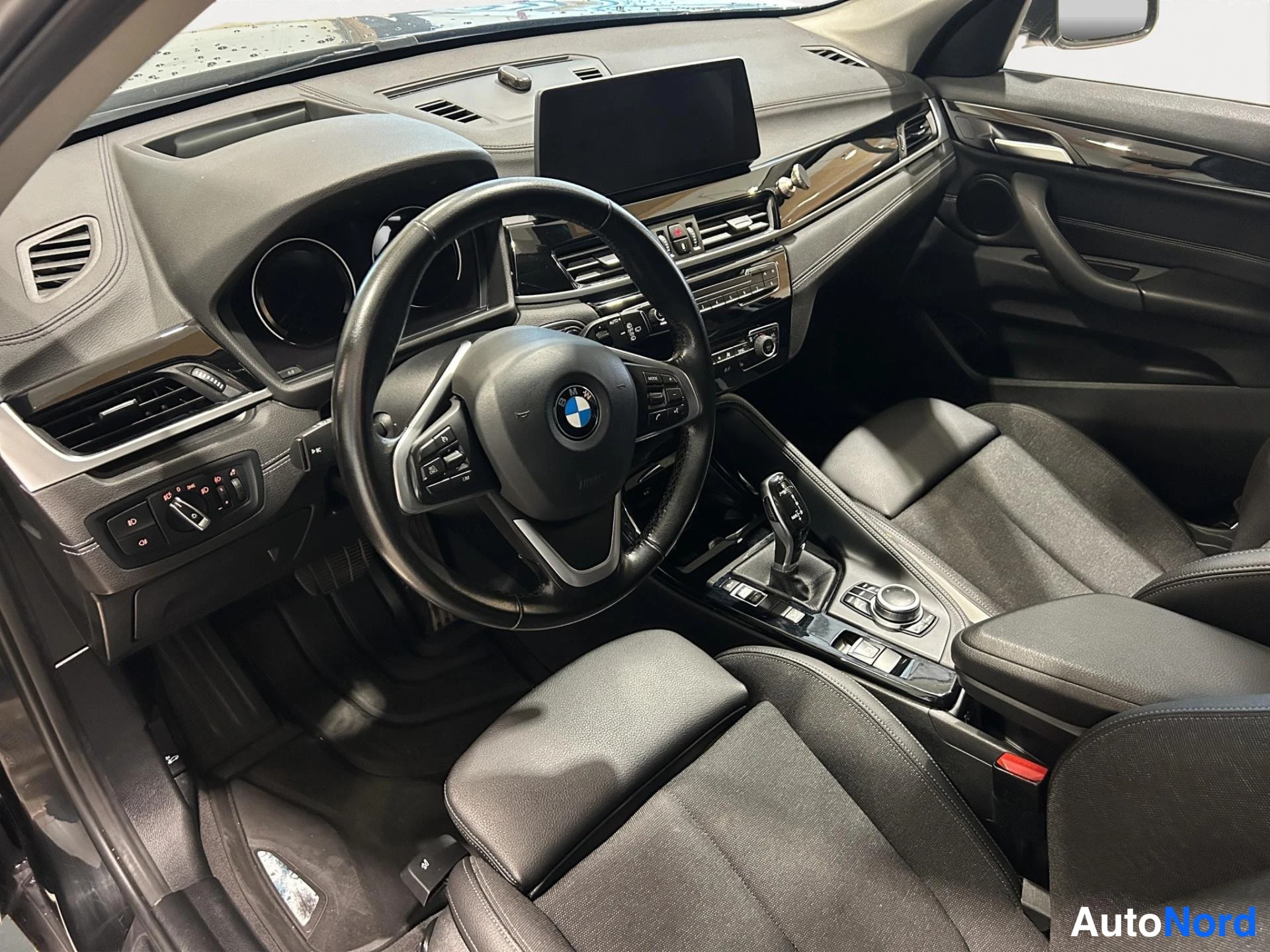 Muu: Auton sisätilat: ohjaamo, ratin ja kojelaudan näkyvä BMW-merkki, mustat penkit ja keskikonsoli.