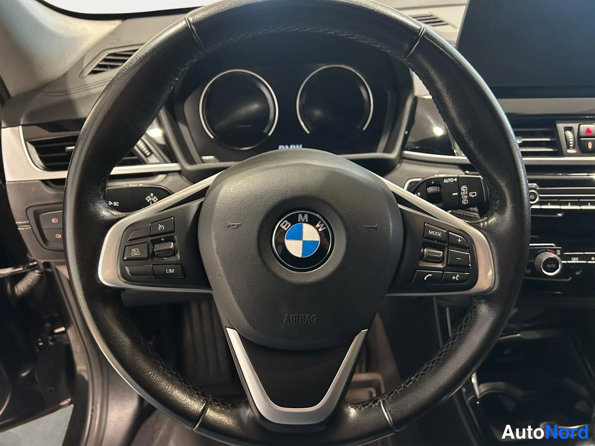 Muu: BMW-merkkinen ohjaustehostinratti kojelaudan mittareiden edessä, ratin monitoiminäppäimet lähikuvassa.
