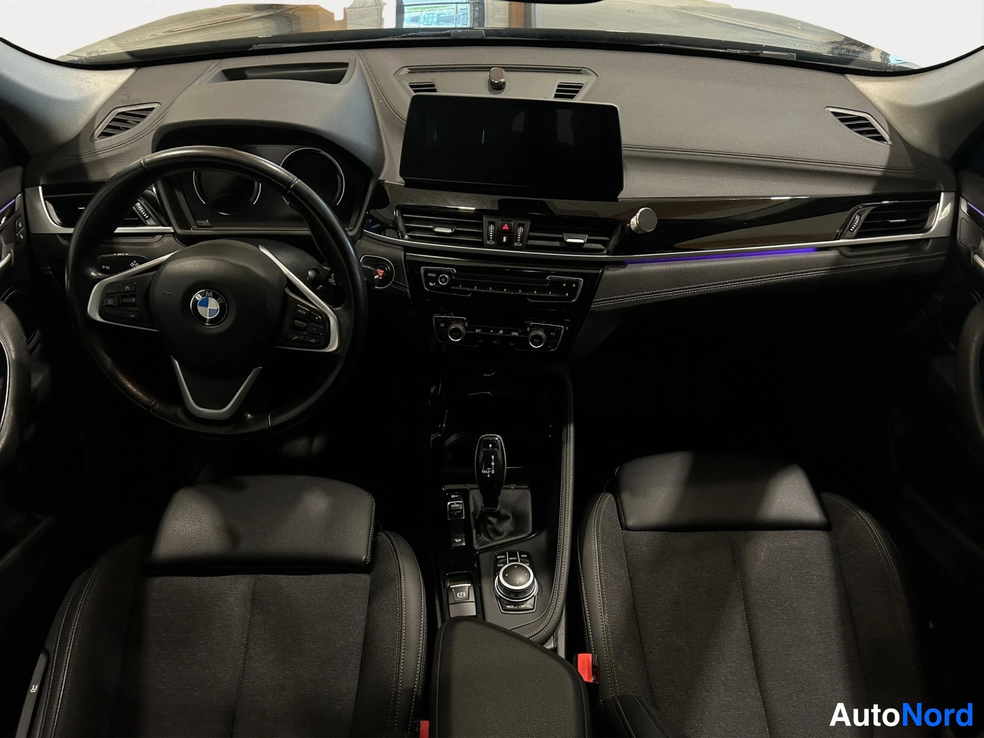 Muu: Auton sisätilat etualalta: BMW-ohjauspyörä, tumma kojelauta, keskikonsolissa automaattivaihteen valitsin, iDrive-ohjain ja nouseva näyttö, kaksi etuistuinta.