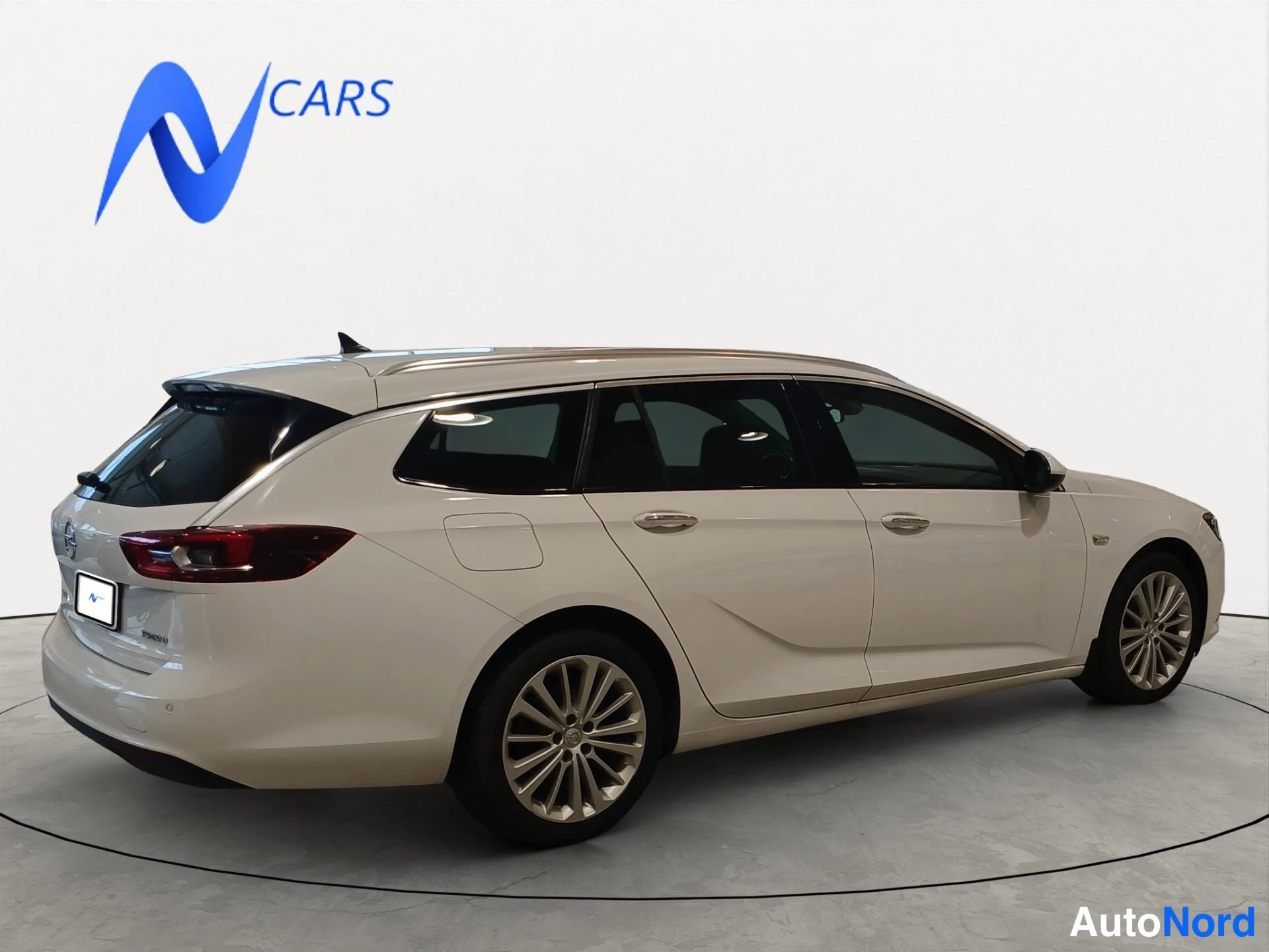 Takaviisto: Opel Insignia -farmarin takaosan kolmasosan näkymä vasemmalta takaa valoisassa studiossa