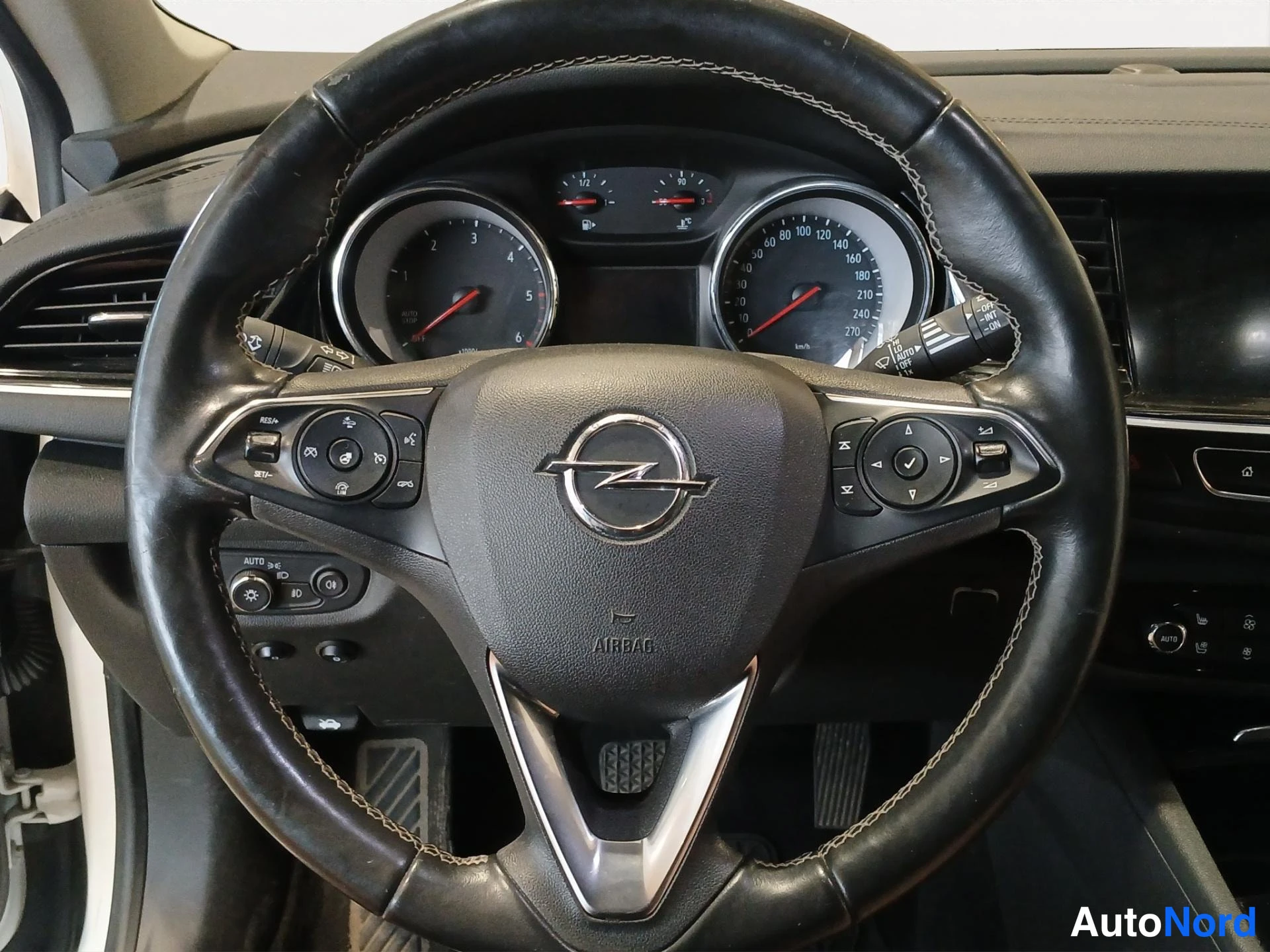 Muu: Ohjauspyörän lähikuva Opel-merkillä: mittaristo, nappiryhmät ja AIRBAG-teksti näkyvät.
