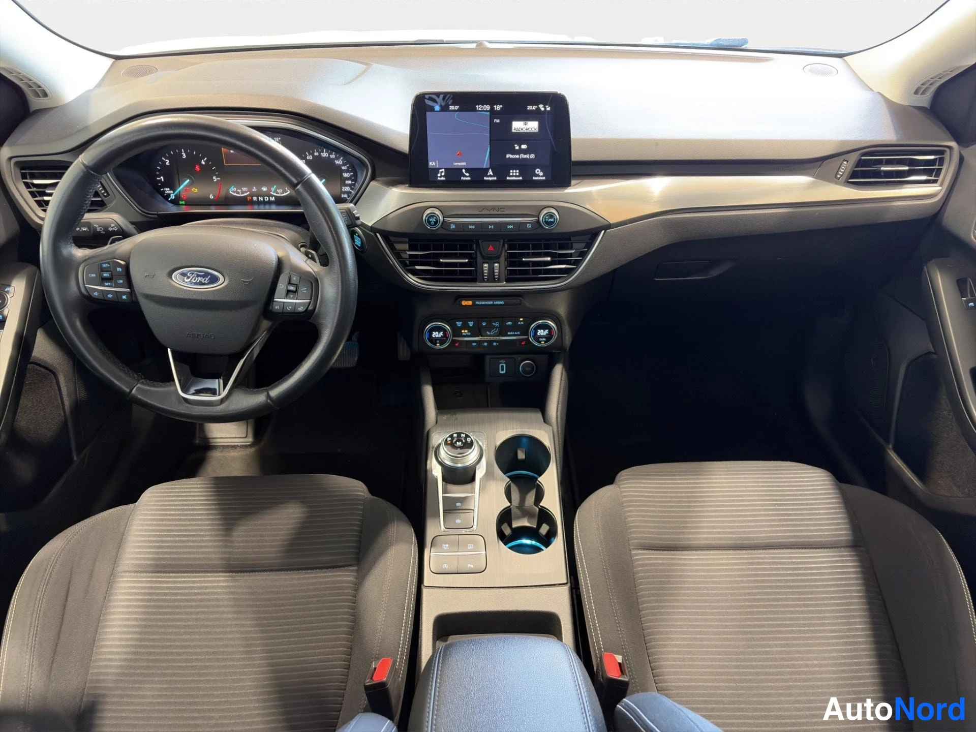 Muu: Ohjaamo edestä: Ford-ohjauspyörä, keskikonsolin automaatiamännikka, tummat kangasistuimet ja navigointinäyttö.