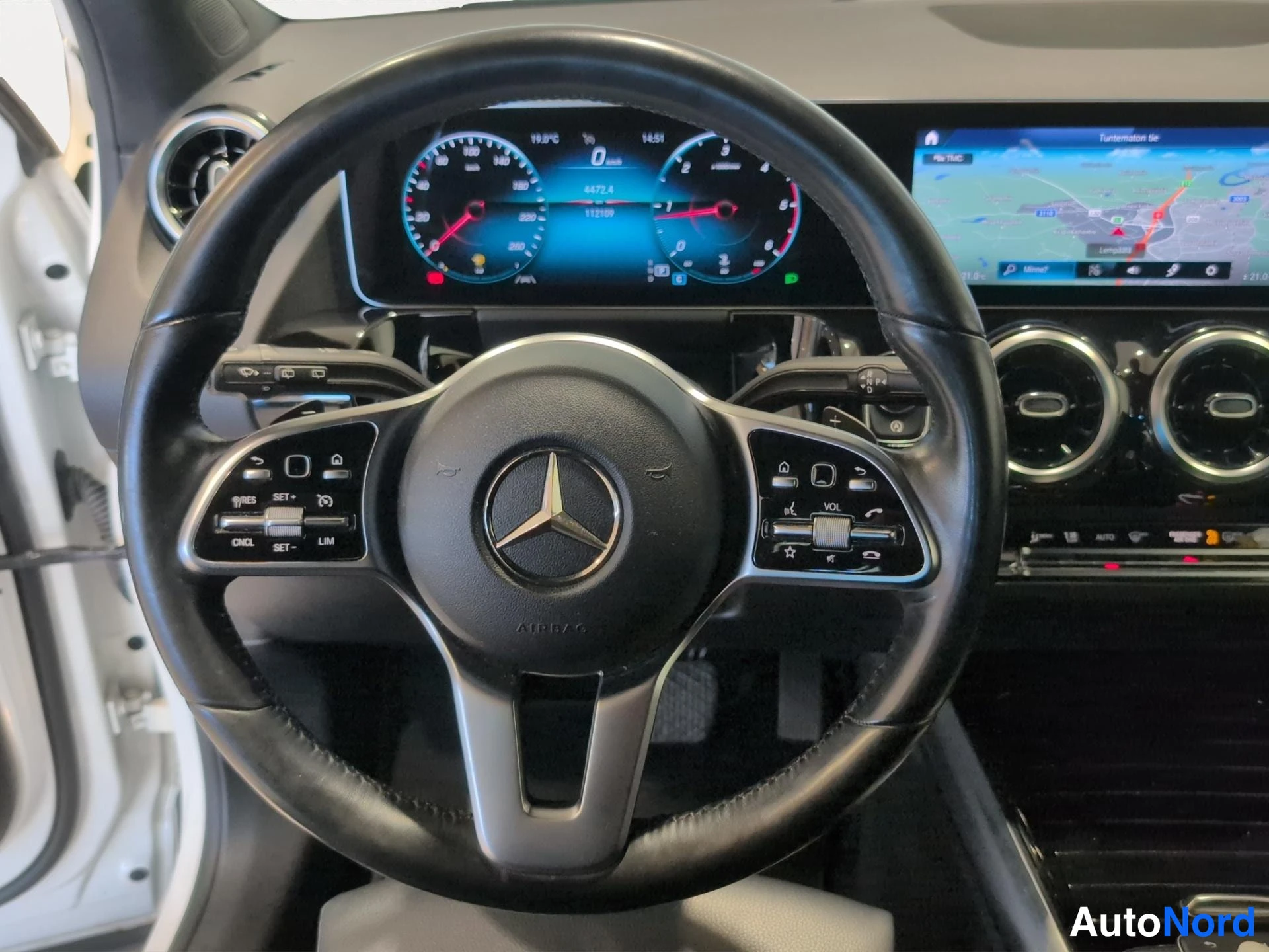 Muu: Ohjaustilanne Mercedes-Benzissä: Multifunktio-ohjauspyörä, digitaalinen mittaristo ja kartta näyttävä infotainment-näyttö.