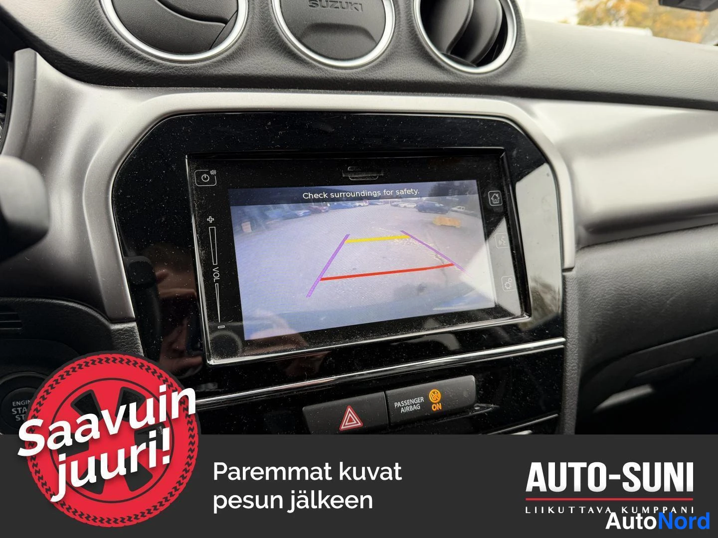 Muu: Sisäkuvat: kojelaudan näyttö, joka näyttää takakameran kuvan tekstillä 'Check surroundings for safety.'