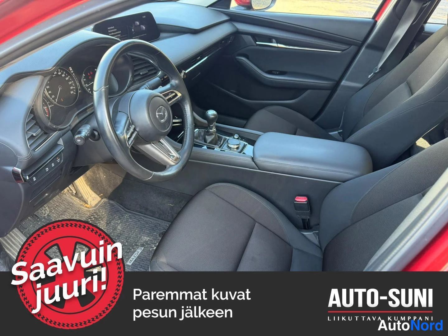 Etuviisto, nokka oikealle: Sisäkuva: manuaalivaihteisto ja Mazda-ohjauspyörä, tummansininen matto.