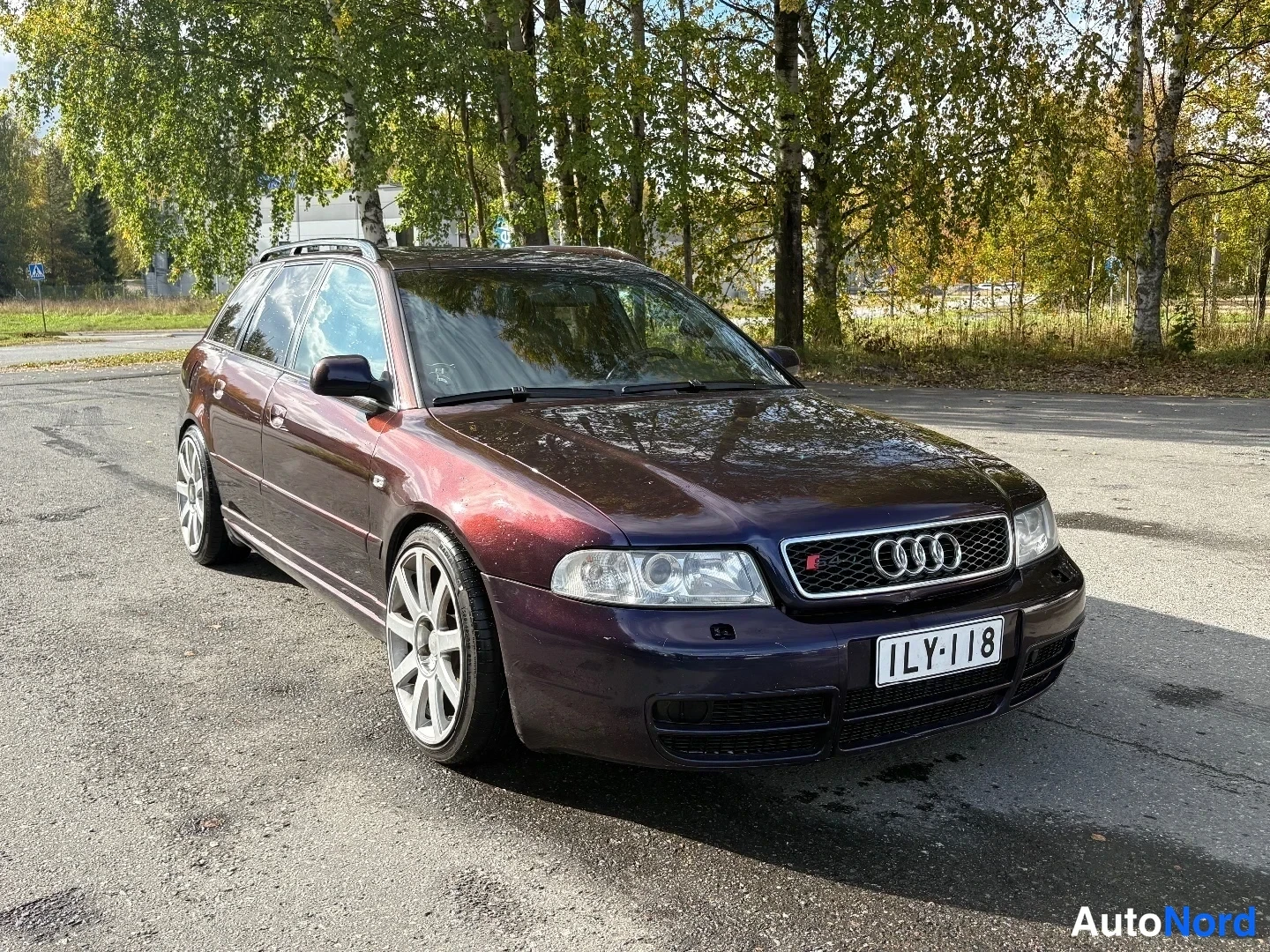Etuviisto, nokka oikealle: Tummansinisen violetti Audi A4 -farmari edestä oikealta kuvattuna, kattokaiteet, hopeavanteet ja rekisteritunnus.