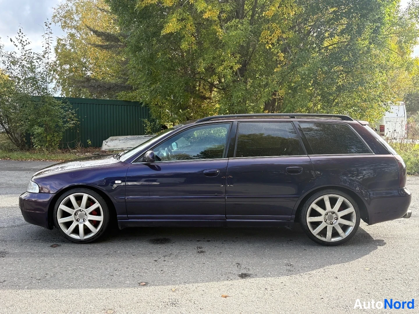 Sivulta: Tummansinisen violetti Audi A4 -farmari sivulta vasemmalta, kattokaiteet ja isot hopeavanteet punaisilla jarrusatuloilla.