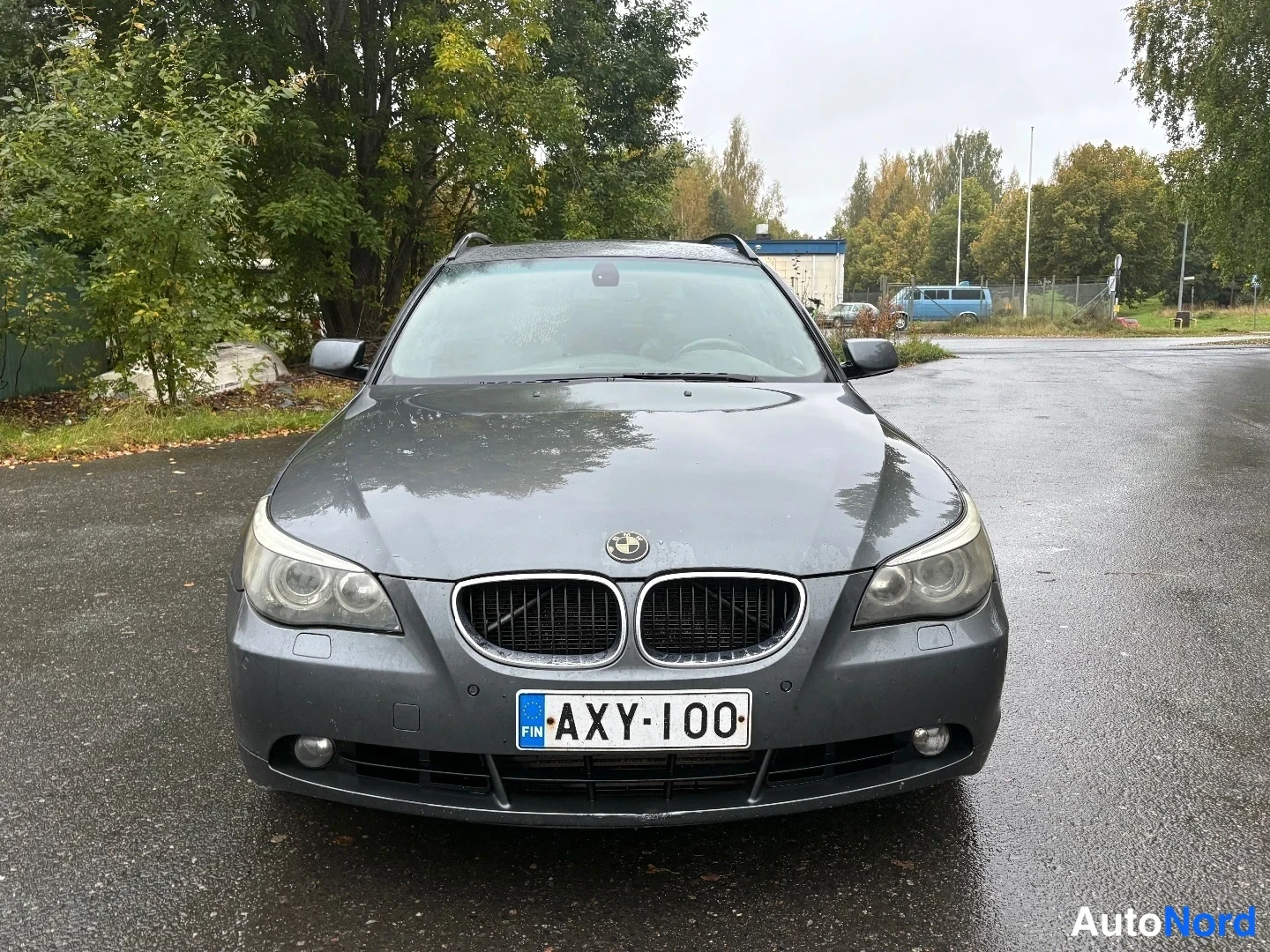 Edestä: Tummanharmaan BMW-farmariauton edessäpäin otettu kuva; etusäleikkö, BMW-merkki ja etuvalot suoraan vastapäätä. Rekisterikilpi.