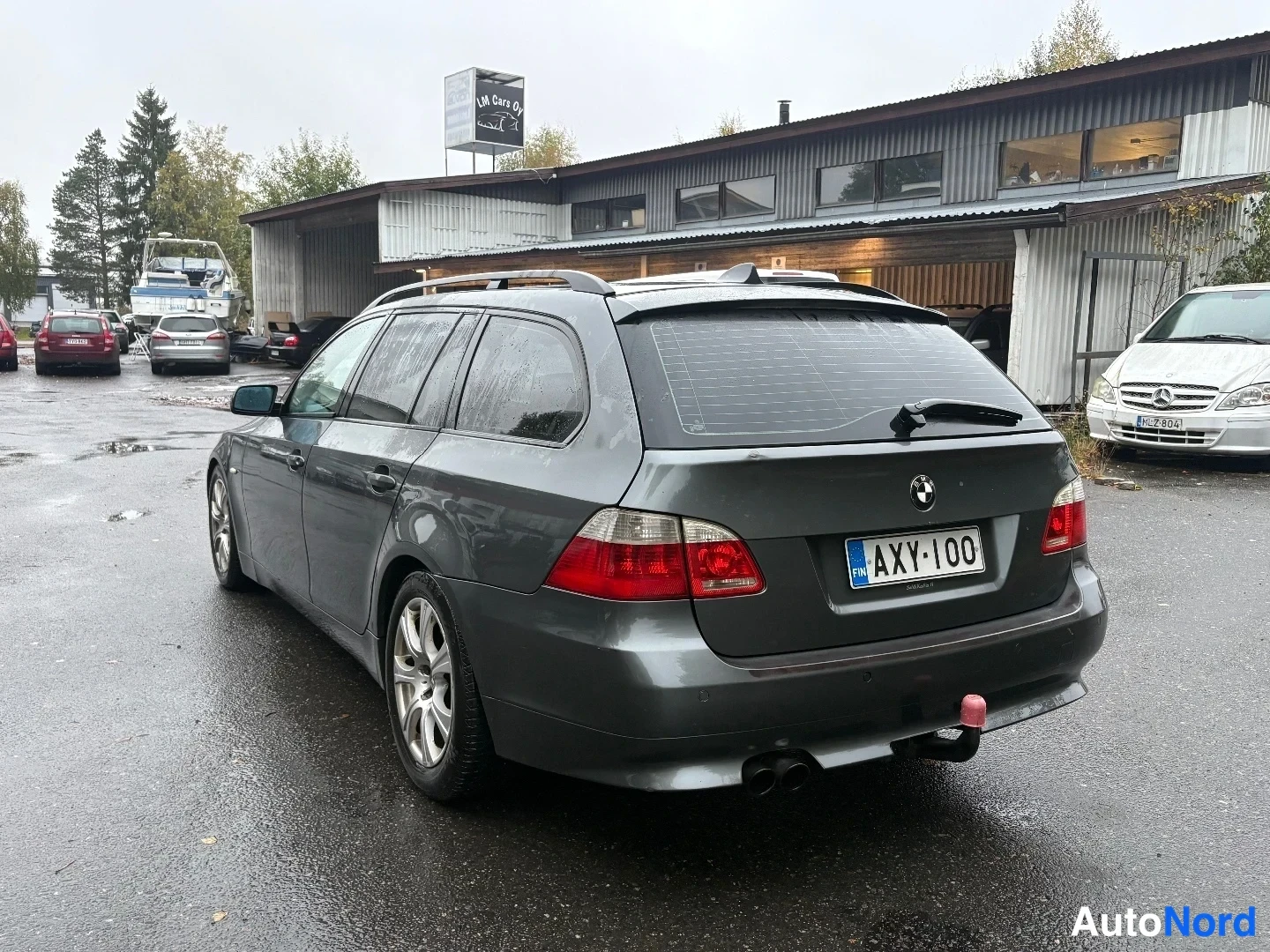 Takaviisto: BMW 5-sarjan farmari takaa viistosti kuvattuna, takavalot, rekisterikilpi ja takakytkimen pallo näkyvissä.