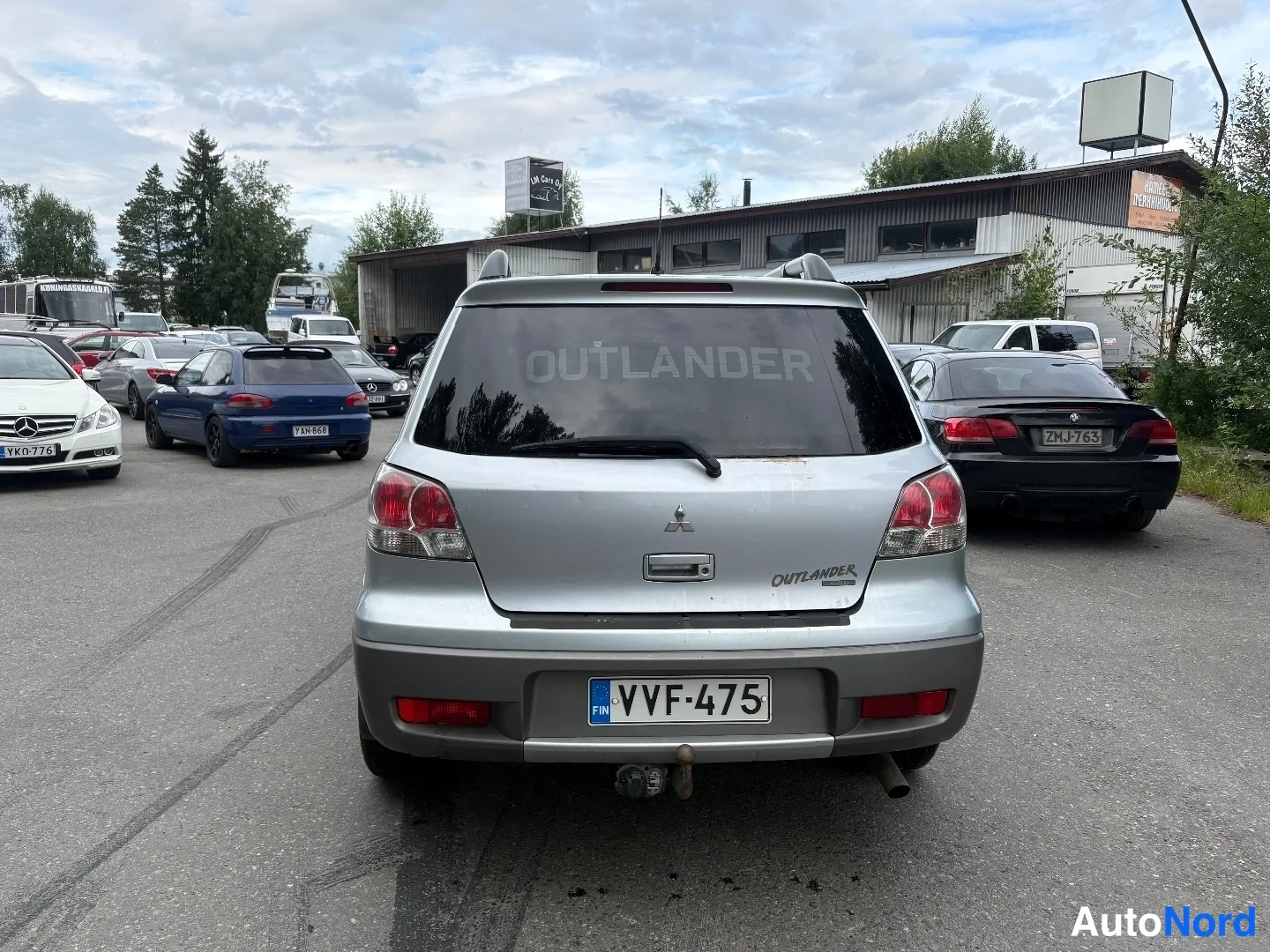 Takaa: Hopeanvärinen Mitsubishi Outlander suoraan takaa, rekisterikilpi ja OUTLANDER-teksti takalasin alaosassa.