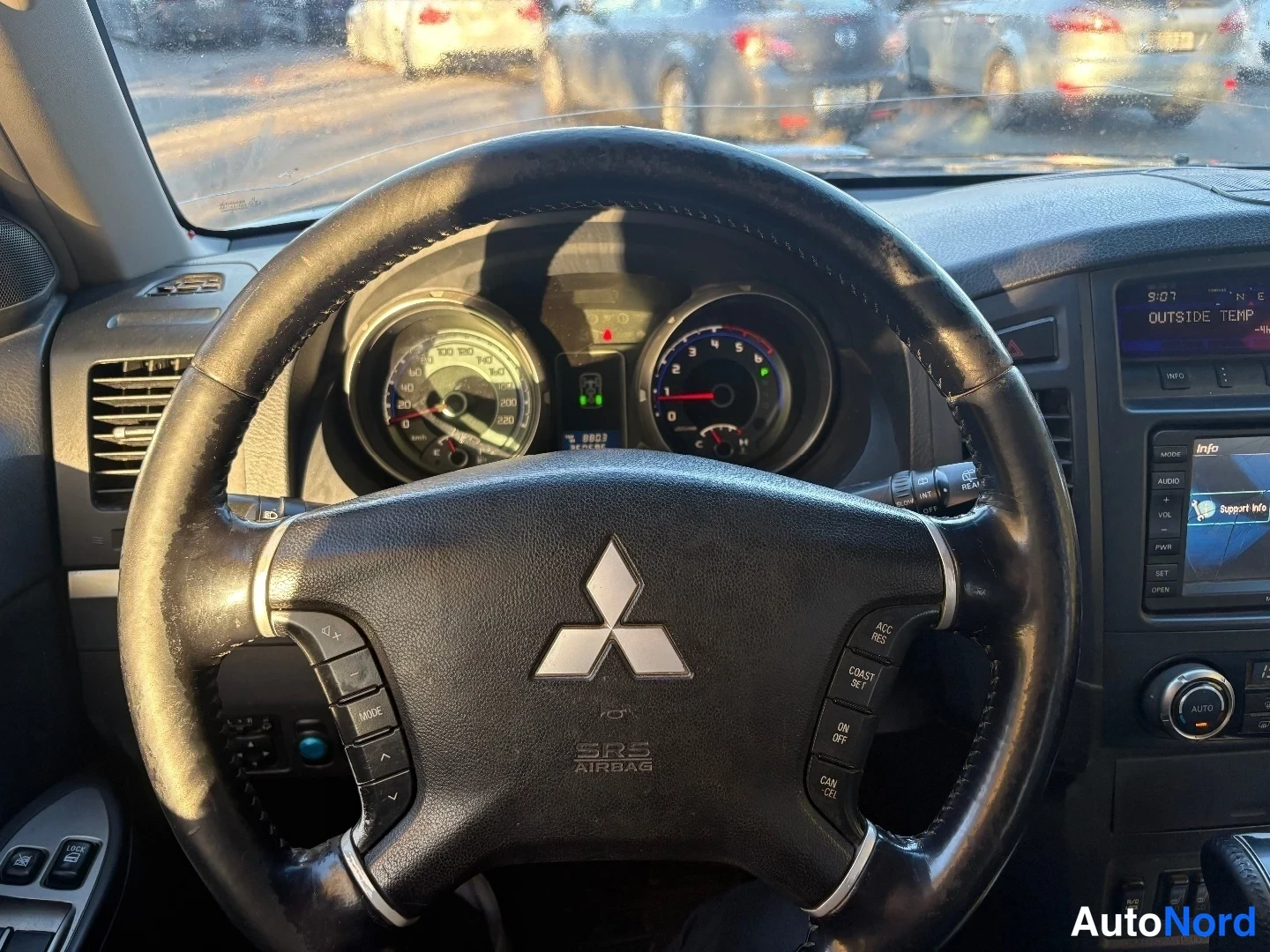 Muu: Lähikuva Mitsubishi-ohjauspyörästä, jossa SRS AIRBAG -merkintä ja ACC-, RES- ja COAST SET -napit; takana mittaristo.