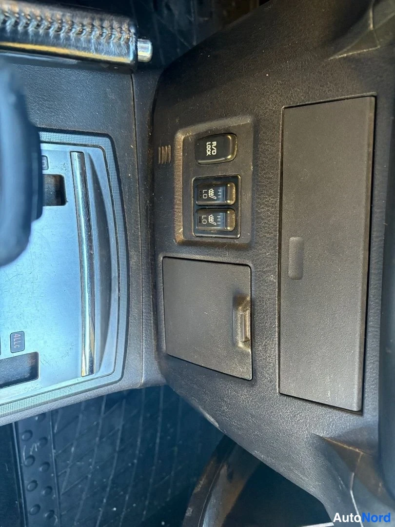 Yksityiskohta: Kojelaudan kytkimia: R/D LOCK -painike ja kaksi kytkinryhmää mustassa keskikonsolissa.