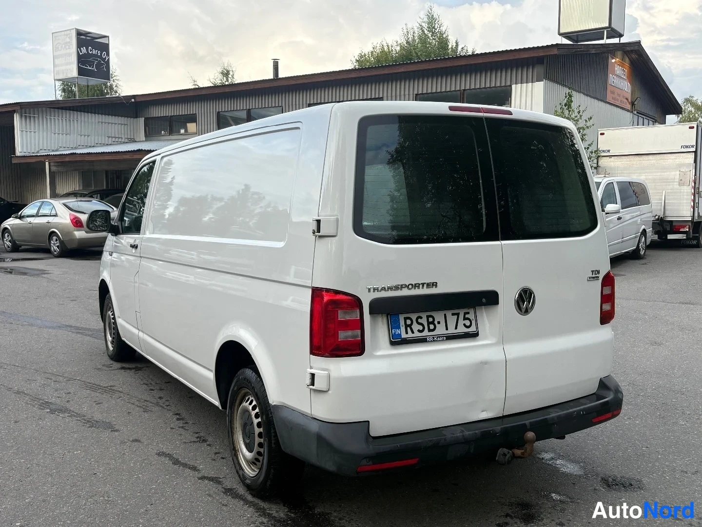 Takaviisto: Valkoisen Volkswagen Transporterin takakolmasosan kuva; rekisterikilpi, TDI-merkintä ja takana hinauskeksi.