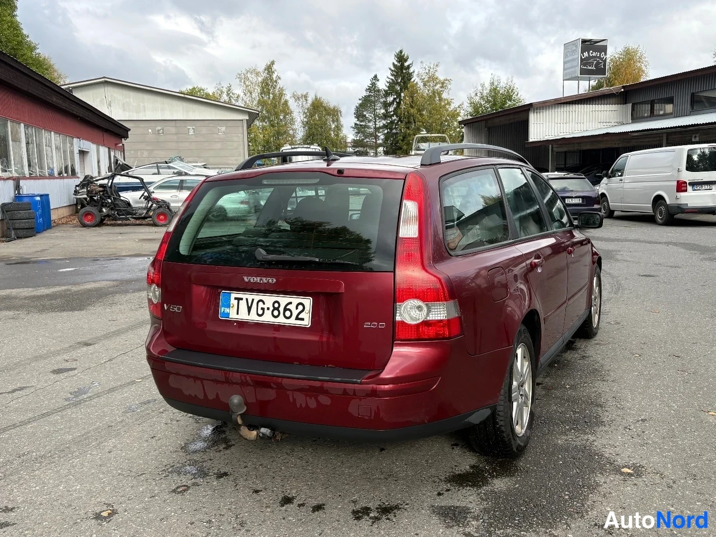 Takaviisto: Tummanpunaisen Volvo V50 -farmarin takaosa ja oikea kylki kolmesta neljäsosakulmasta; rekisteritunnus, kattokaiteet ja vetokoukku näkyvissä.