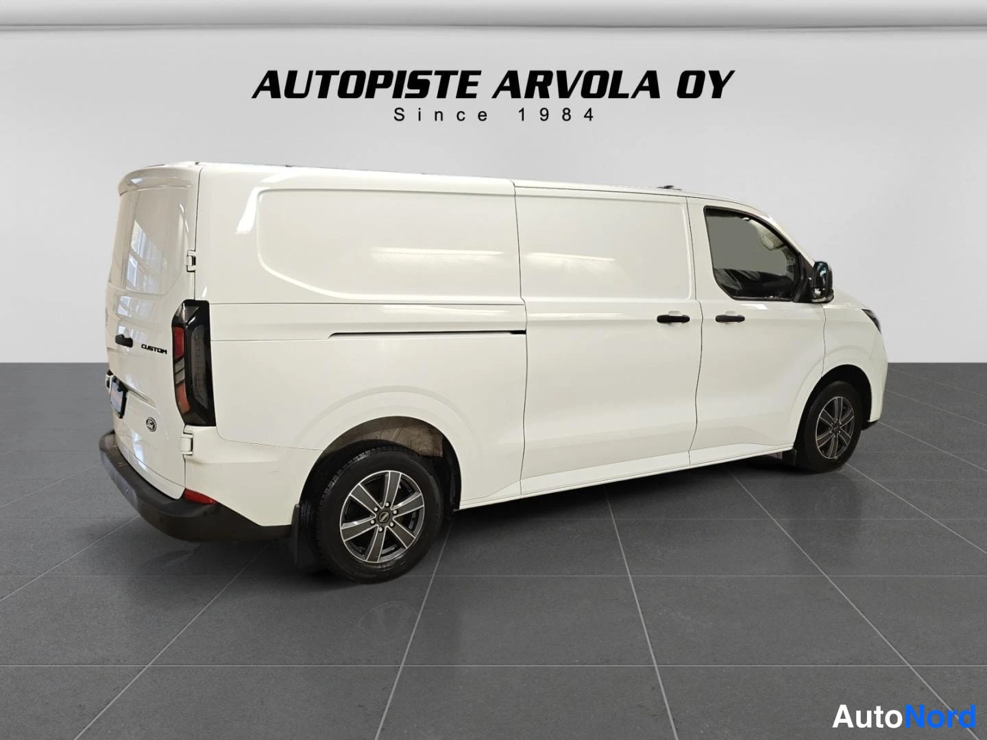 Takaviisto: Ford Transit Custom -pakettiauto takaviistosta vasemmalle, valkoinen korisävy.