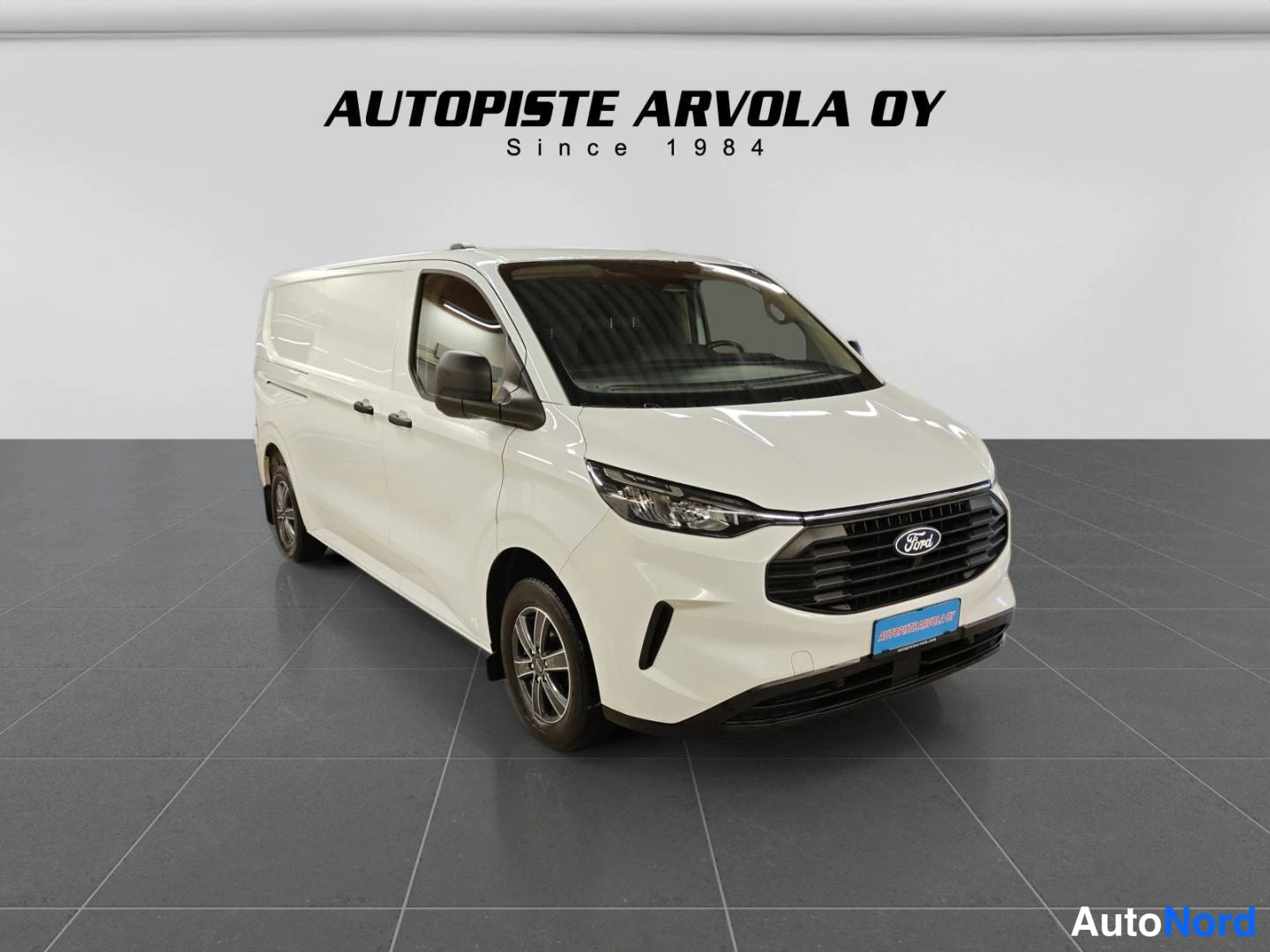 Etuviisto, nokka oikealle: Ford Transit Custom -pakettiauto etuviistosta oikealle, valkoinen korisävy.
