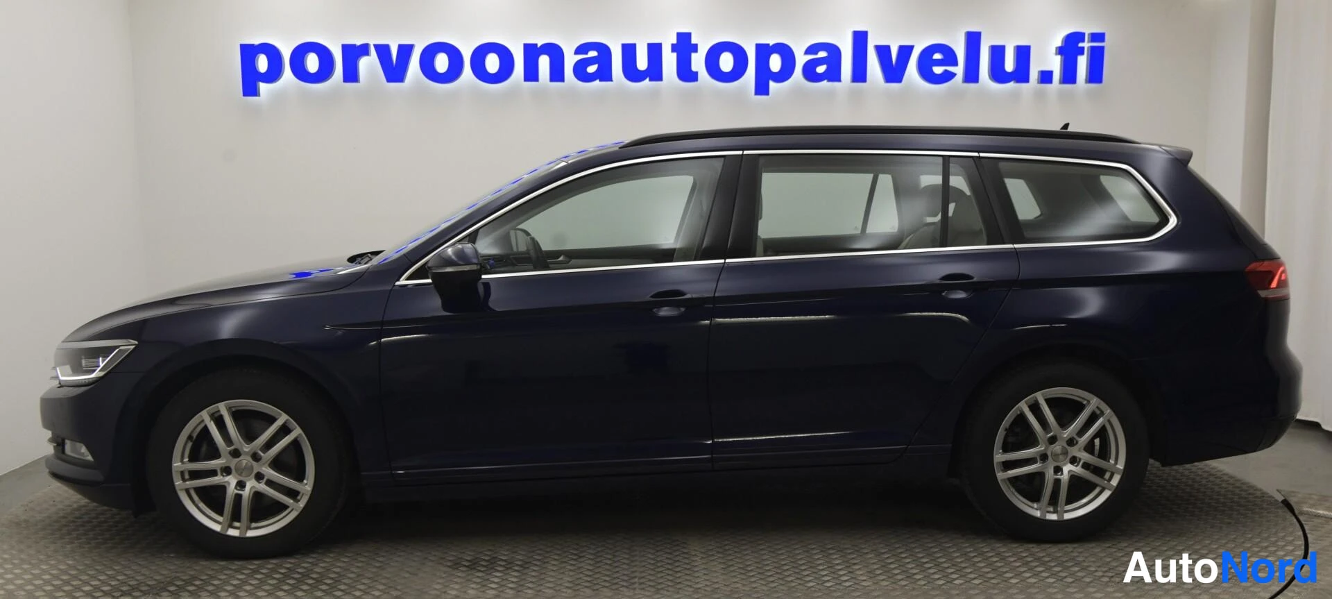 Etuviisto, nokka vasemmalle: Sininen farmariauto vasemmalta sivulta kuvattuna, kylki ja hopeavanteet näkyvät.