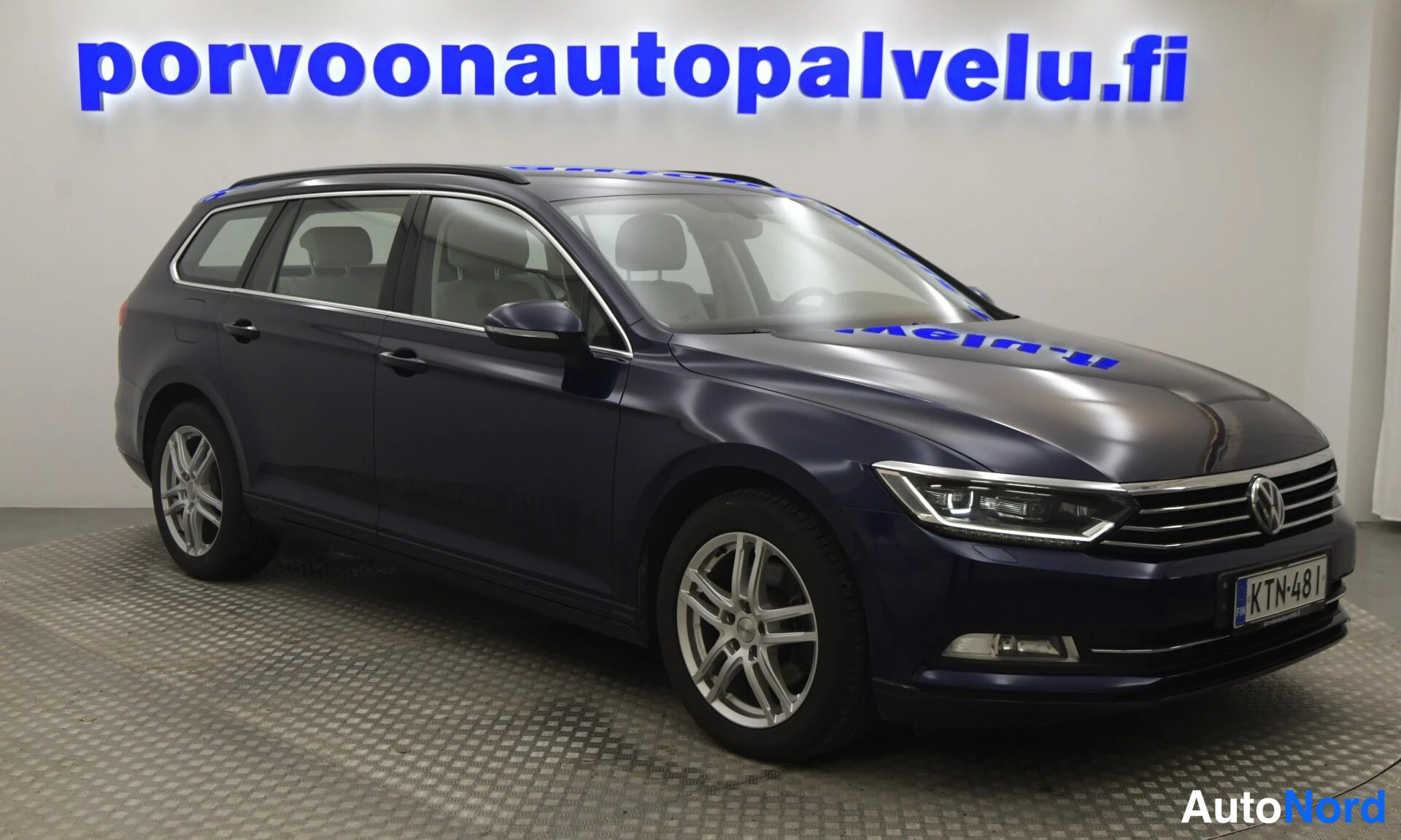 Etuviisto, nokka oikealle: Volkswagen Passat Variant -farmari edestä ja vasemmalta sivulta kuvattuna, tummansininen