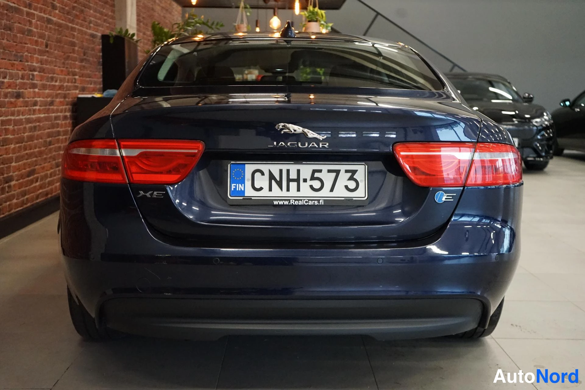 Takaa: Jaguar XE:n takaosa suoraan takaa: rekisterikilpi, XE-merkintä ja JAGUAR-logo. Auto on tummansininen.
