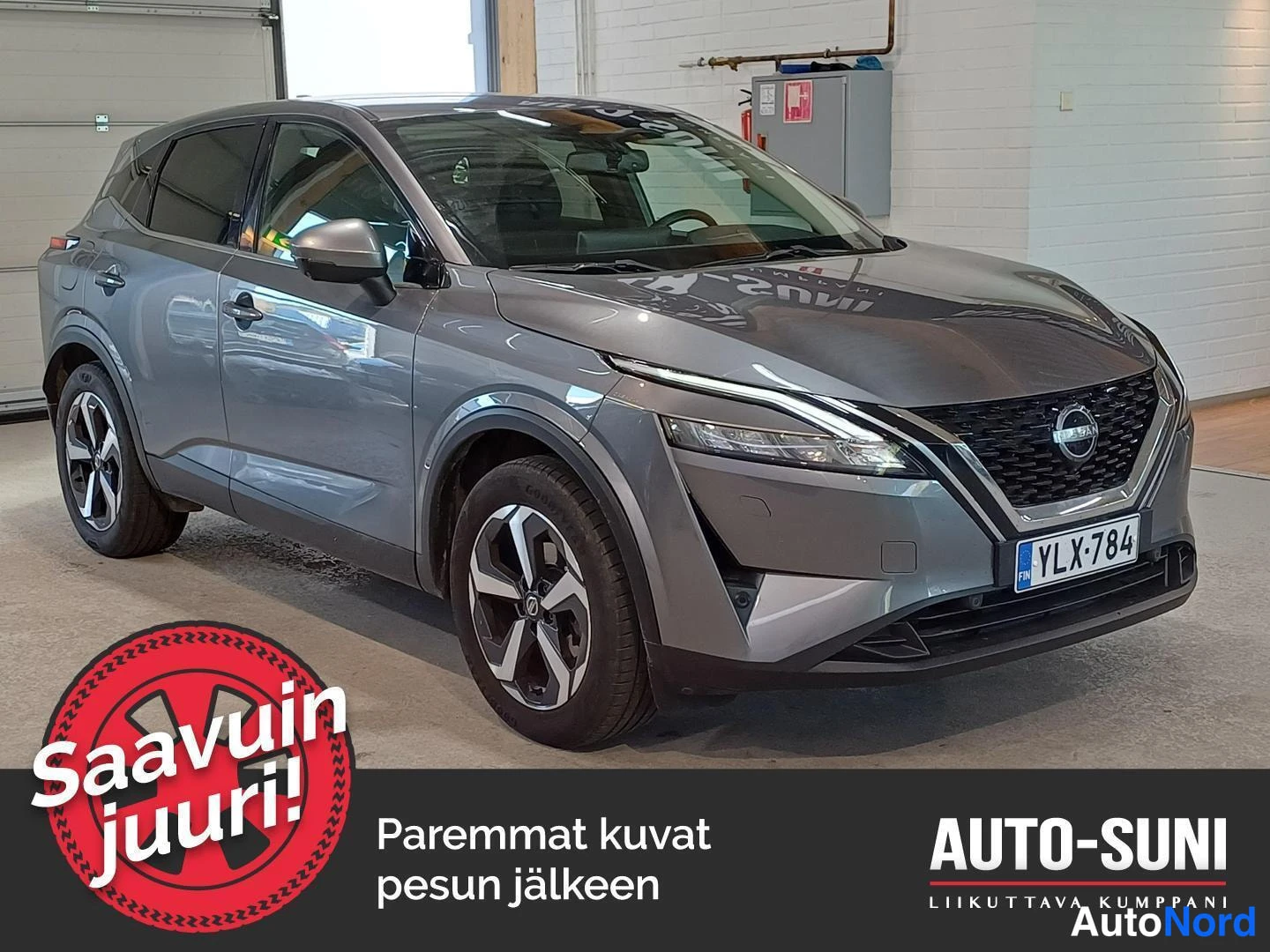 Etuviisto, nokka oikealle: Hopeanharmaa Nissan Qashqai etuviistosta oikealta, etusäleikkö ja rekisterikilpi näkyvät sisätiloissa.