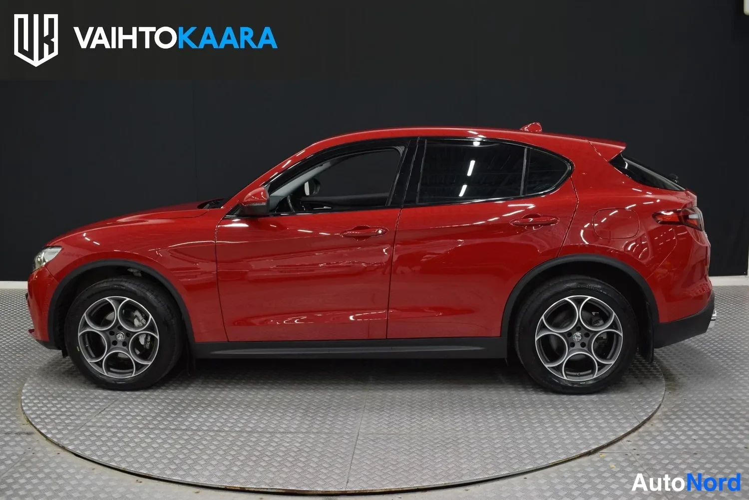 Sivulta: Punainen Alfa Romeo Stelvio sivulta vasemmalle näkyvillä, takaveto ja oikea sivu