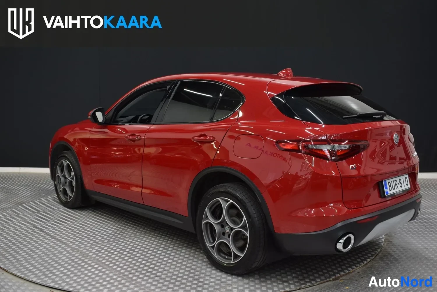 Takaviisto: Punainen Alfa Romeo Stelvio takaa vasemmalle näkyvissä, takapää ja vasen sivu