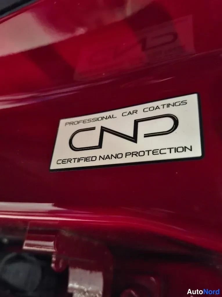 Yksityiskohta: Punaisessa koriosassa valkoinen CND-tarra, teksti PROFESSIONAL CAR COATINGS – CERTIFIED NANO PROTECTION.