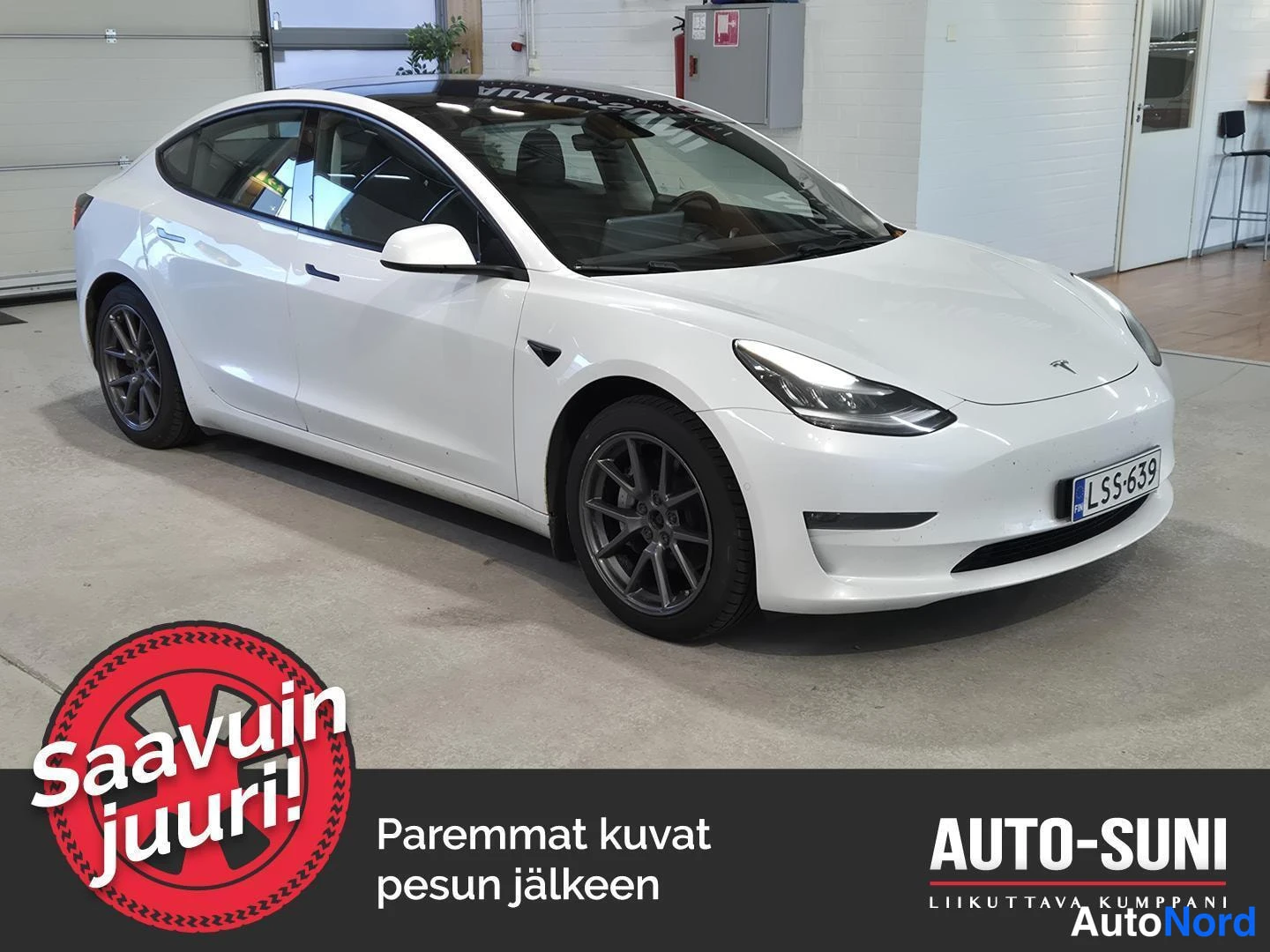 Etuviisto, nokka oikealle: Valkoinen henkilöauto vinosti etuosasta kuvattuna autotallin sisällä.