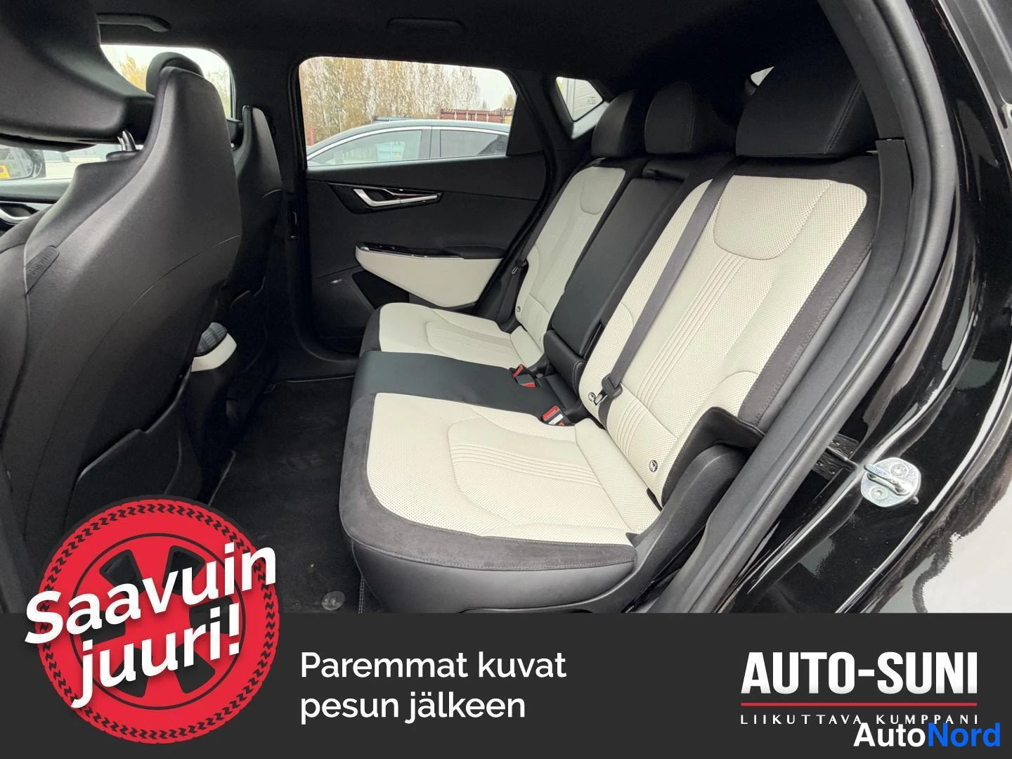 Muu: Takapenkkien 3/4-näkymä avoimesta vasemmasta takaovasta; vaalean beige ja tummat istuimet, tumma ovivuori ja paneeli.