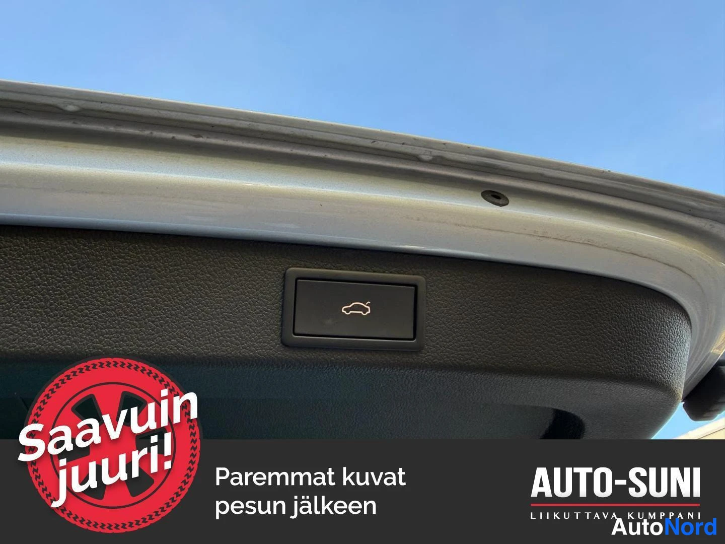 Yksityiskohta: Takaluukun sisäpinnan sähköinen avauspainike: painikkeen symboli (auto nappia painamassa) erottuu selkeästi, takaluukun karmi näkyy.