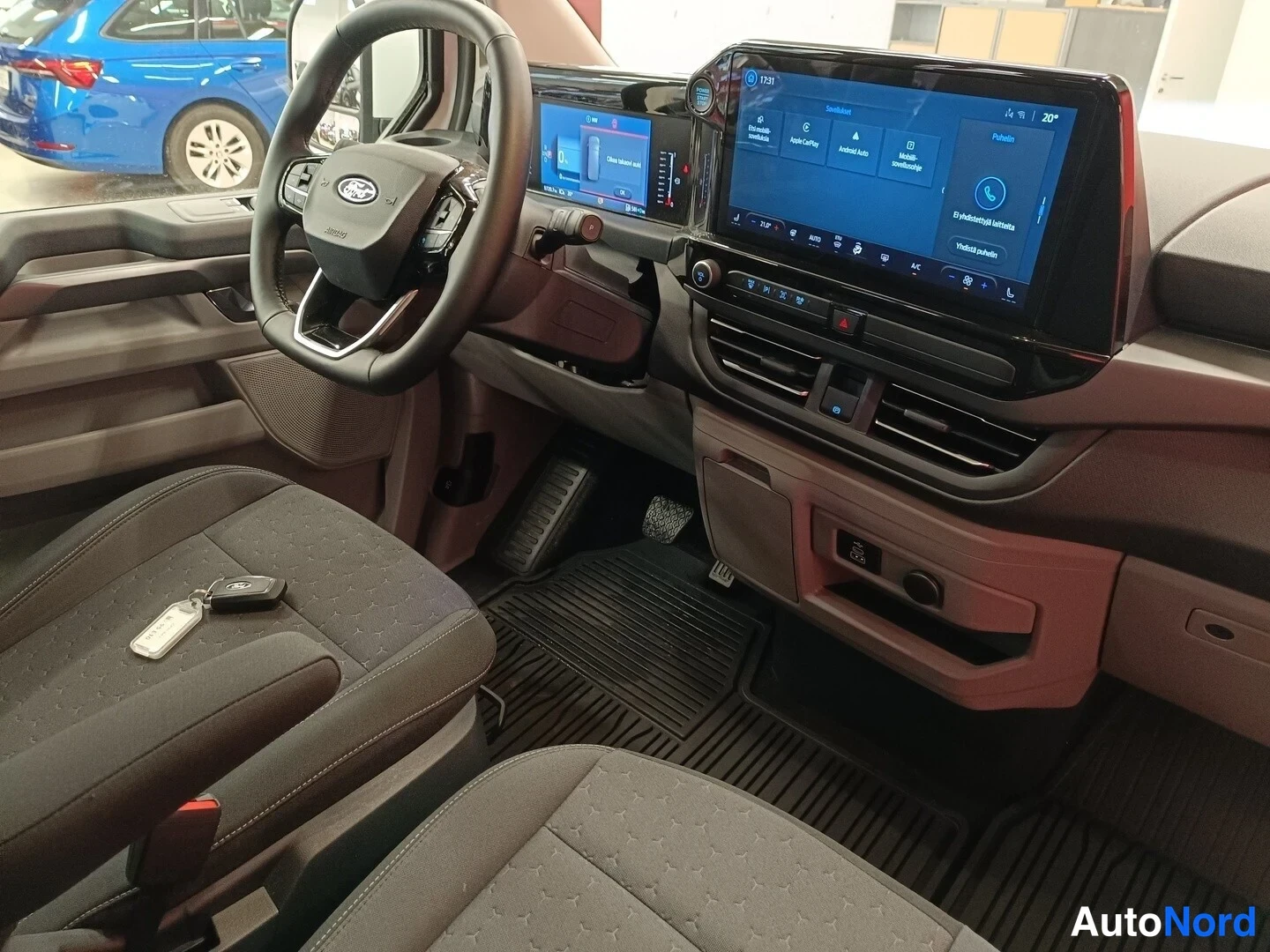 Muu: Ohjaamon näkymä: Ford-merkkinen ohjauspyörä, tekstiilituhkanharmaat penkit, keskinäyttö jossa Sovellukset-paneeli (mm. Apple CarPlay ja Android Autonominen/Auto