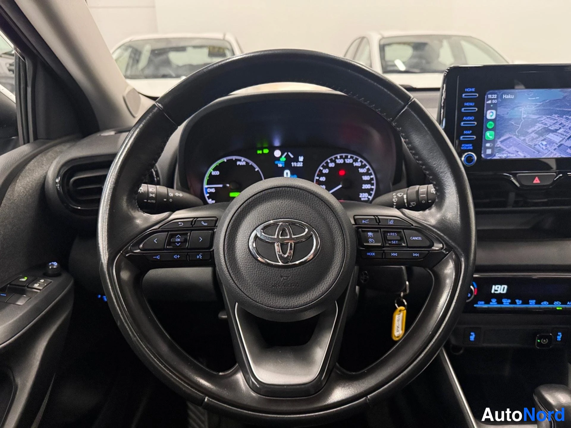 Etuistuimet: Ohjauspyörä Toyota-merkillä, kojelauta ja infotainment-näyttö karttaanäkymällä.