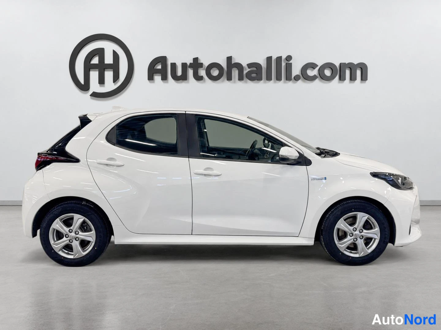 Sivulta: Valkoinen Toyota Yaris sivulta oikealta