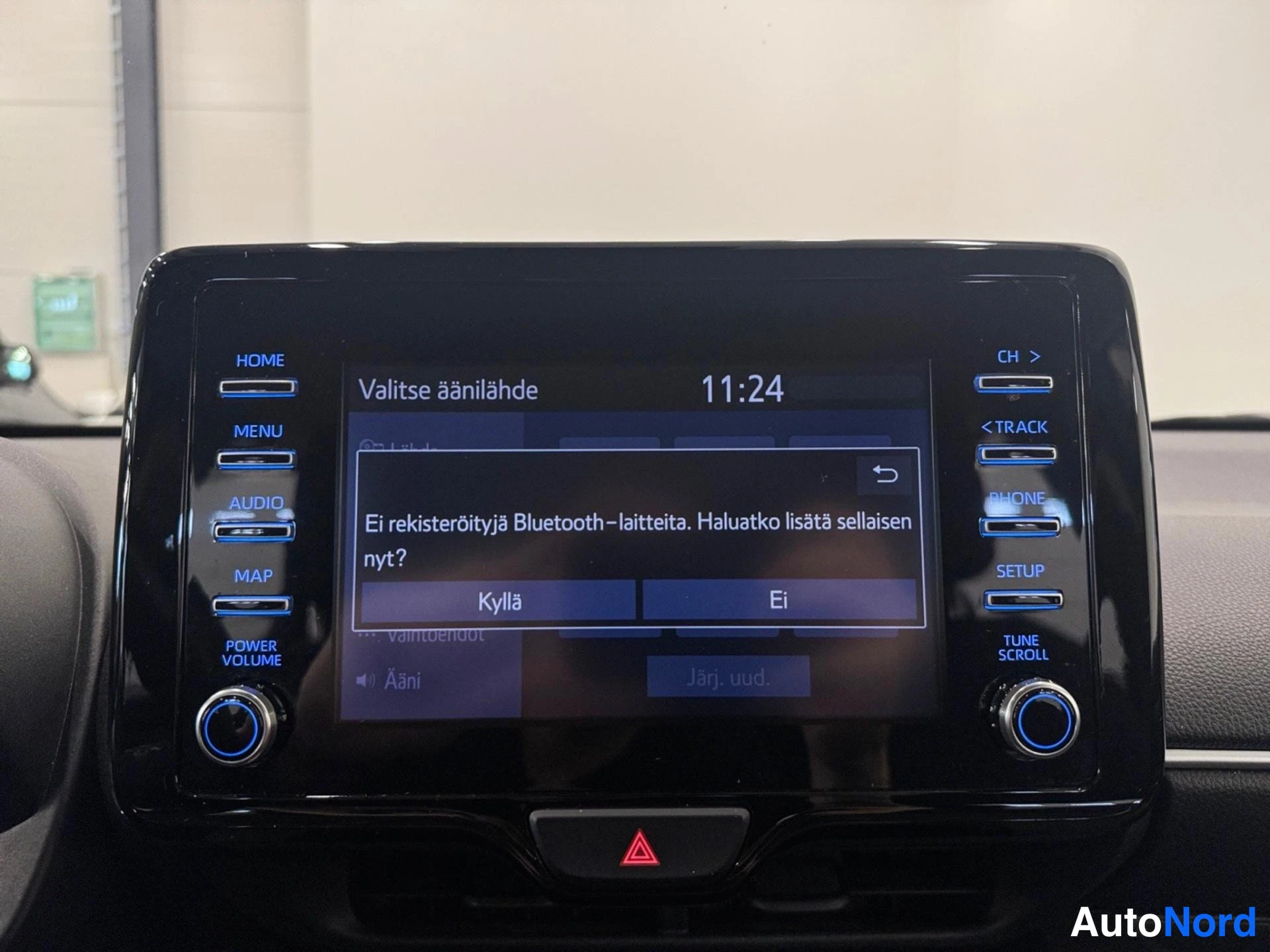 Muu: Auton kojelaudan infotainment-näyttö. Ruudulla lukee 'Valitse äänilähde', kello 11:24 sekä ilmoitus 'Ei rekisteröityjä Bluetooth–laitteita. Haluatko lisätä sell