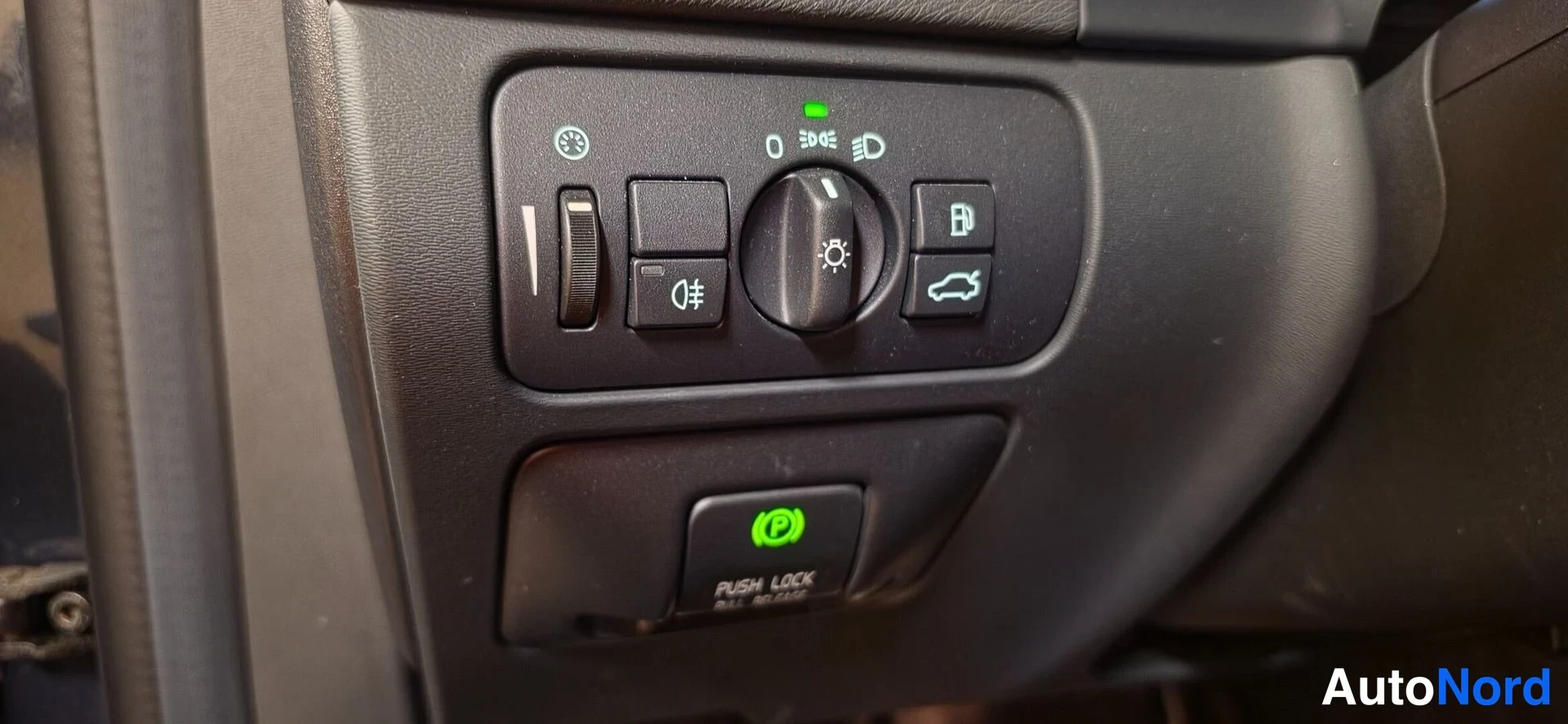 Muu: Valaisinkytkimen paneeli ja sähköinen parkkijarrun nappi, teksti PUSH LOCK ALL BRAKE, vihreä merkkivalo.